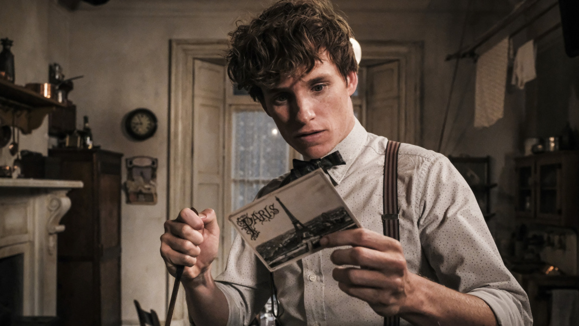 Eddie Redmayne dans le rôle de Newt Scamander lisant une carte postale de Paris.