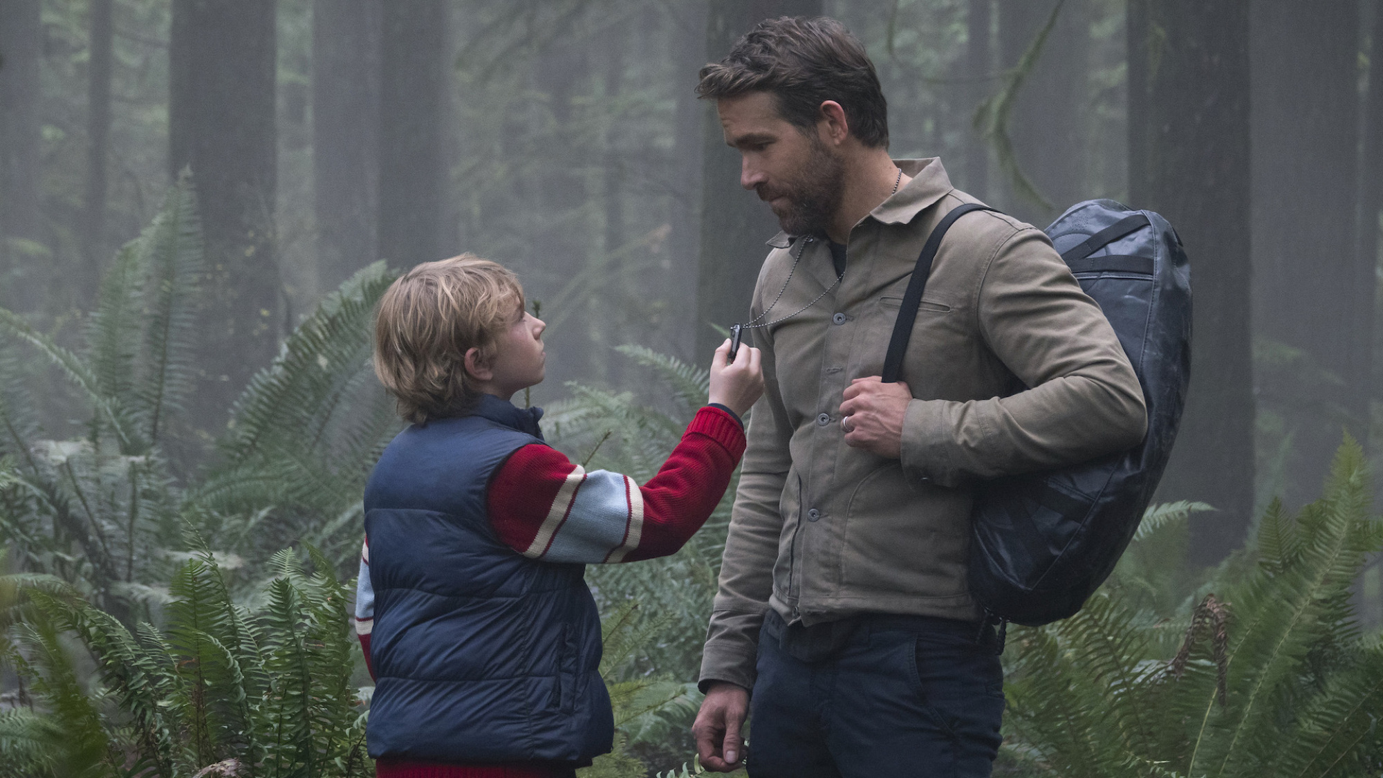 Un homme et un garçon se regardent dans la forêt : Walker Scobell et Ryan Reynolds dans 