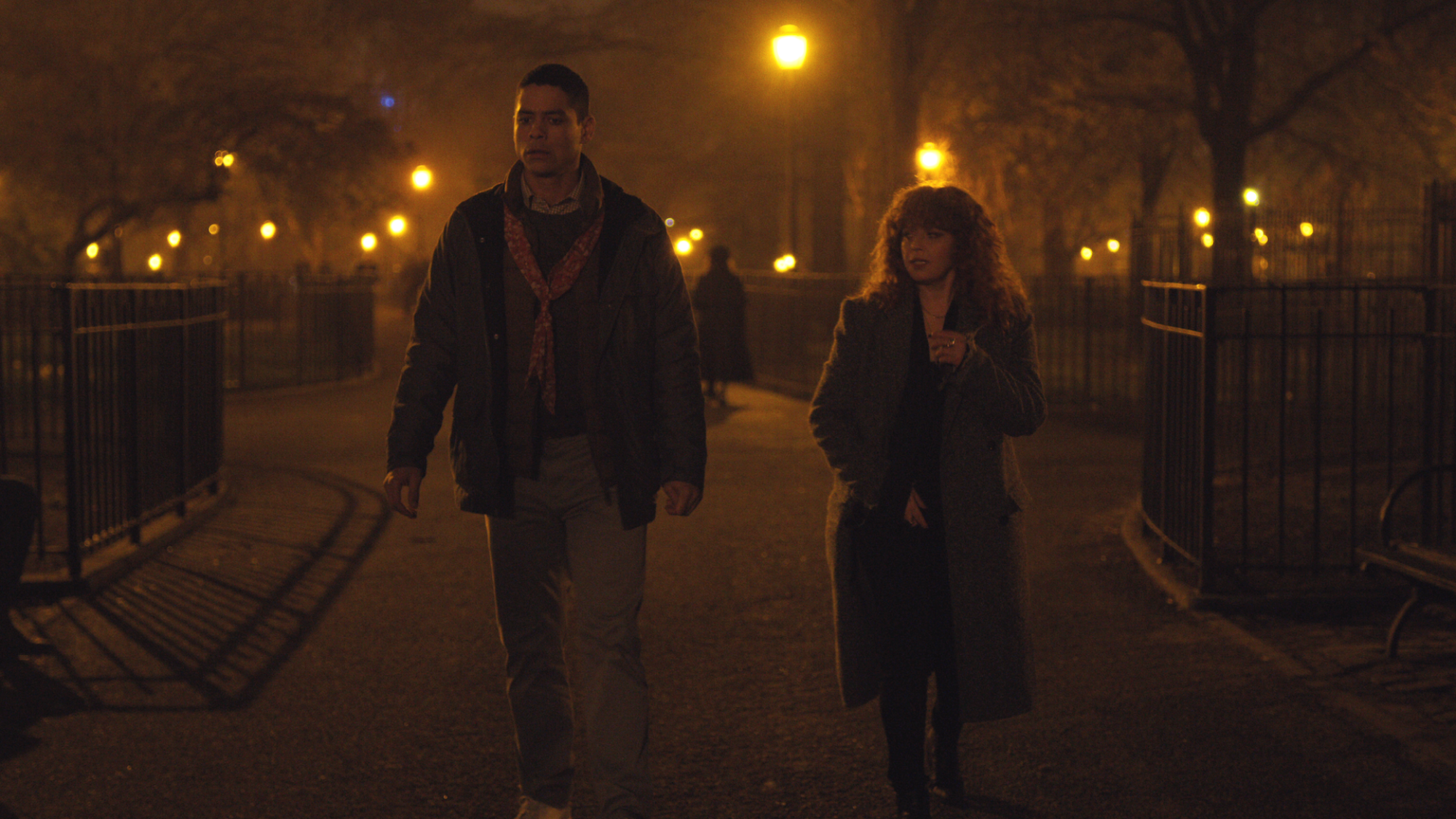 Un homme et une femme marchent dans un parc de New York la nuit ;  encore de 