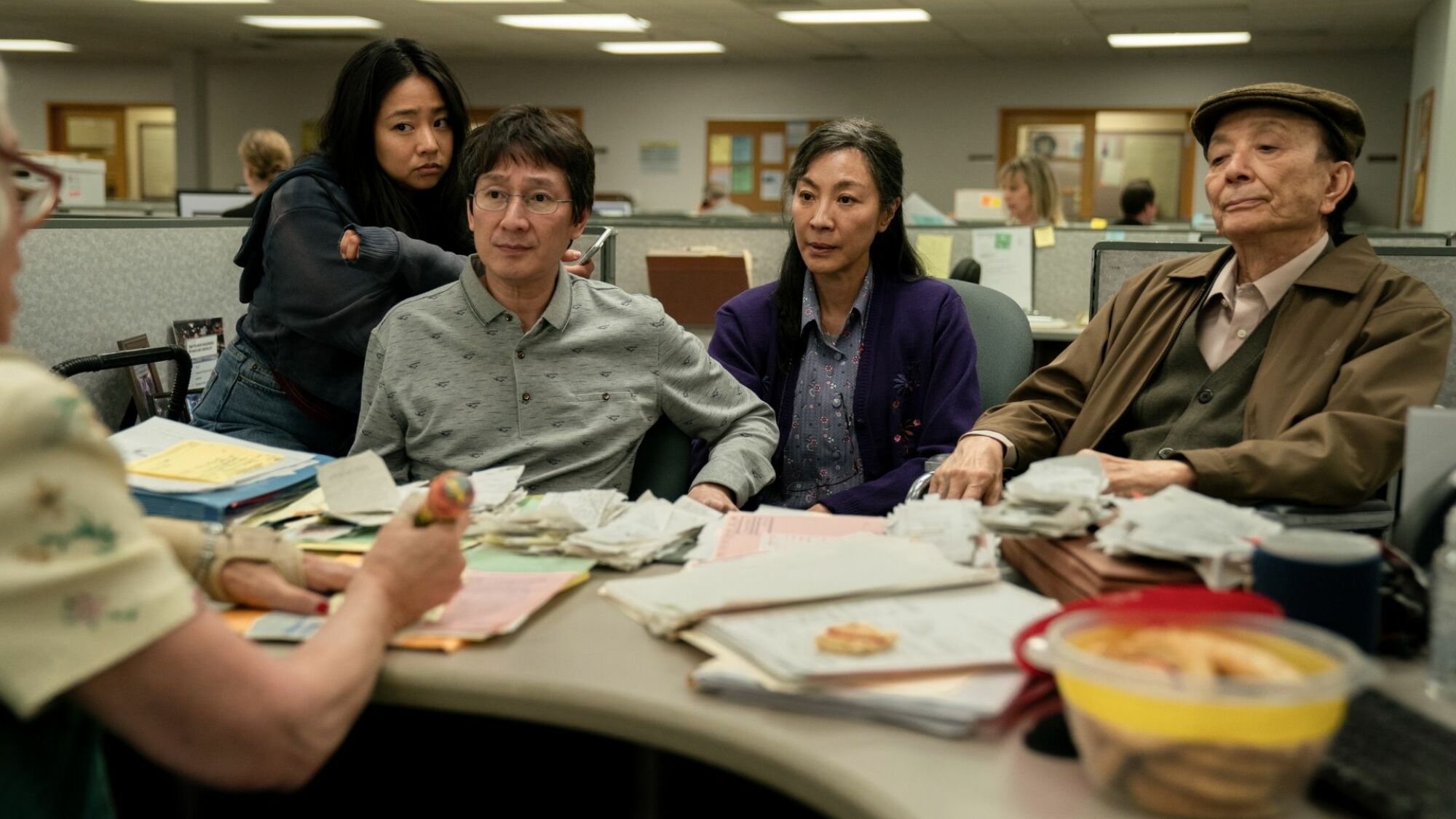 Une famille asiatique est assise dans une cabine, recroquevillée sur un bureau rempli de reçus. 
