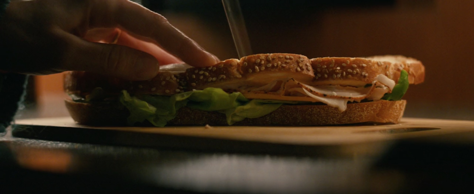 Un sandwich sur le point d'être coupé en deux avec un couteau.
