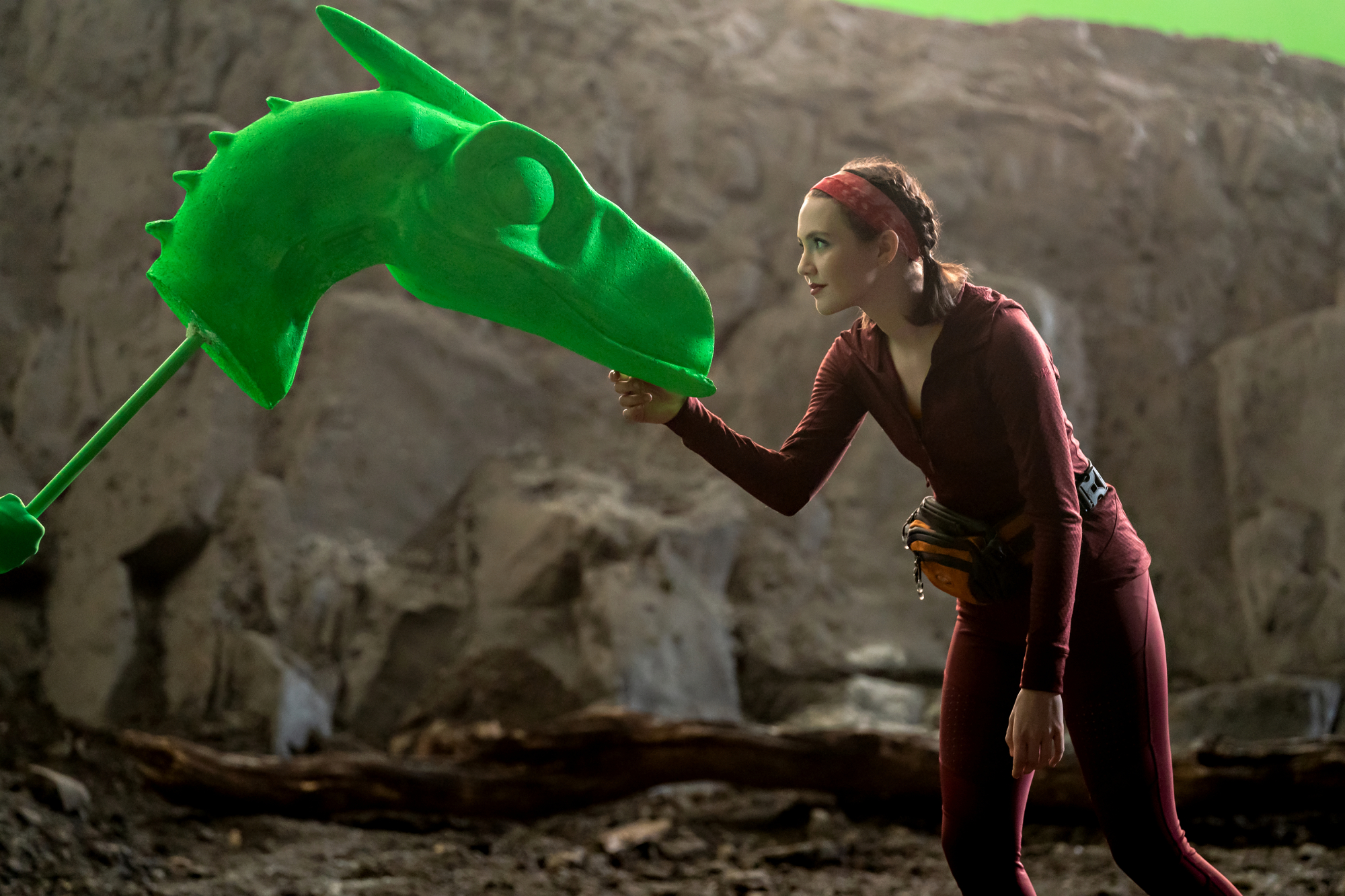 Une jeune femme atteint sous le menton d'une tête de dinosaure à écran vert.