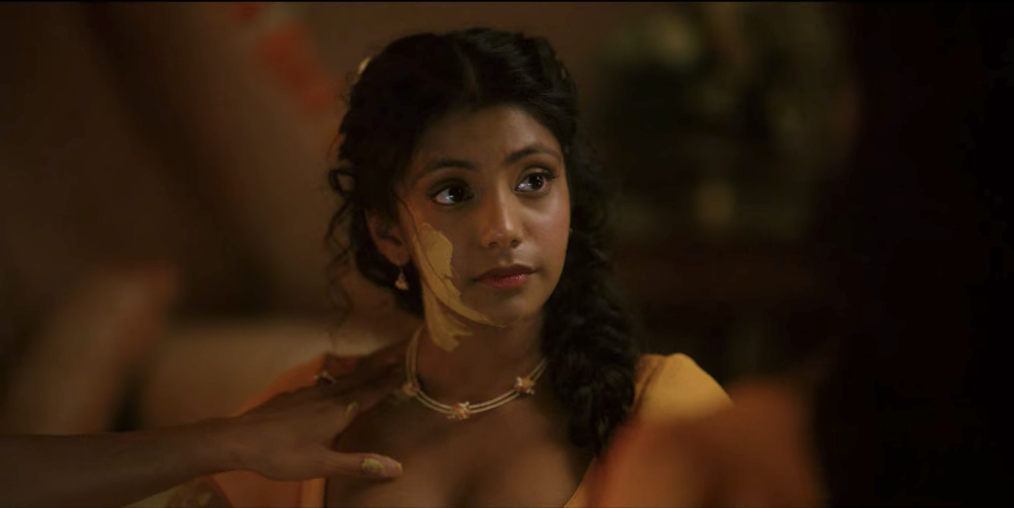 Une jeune femme indienne avec de la pâte de curcuma sur la joue ;  encore de 