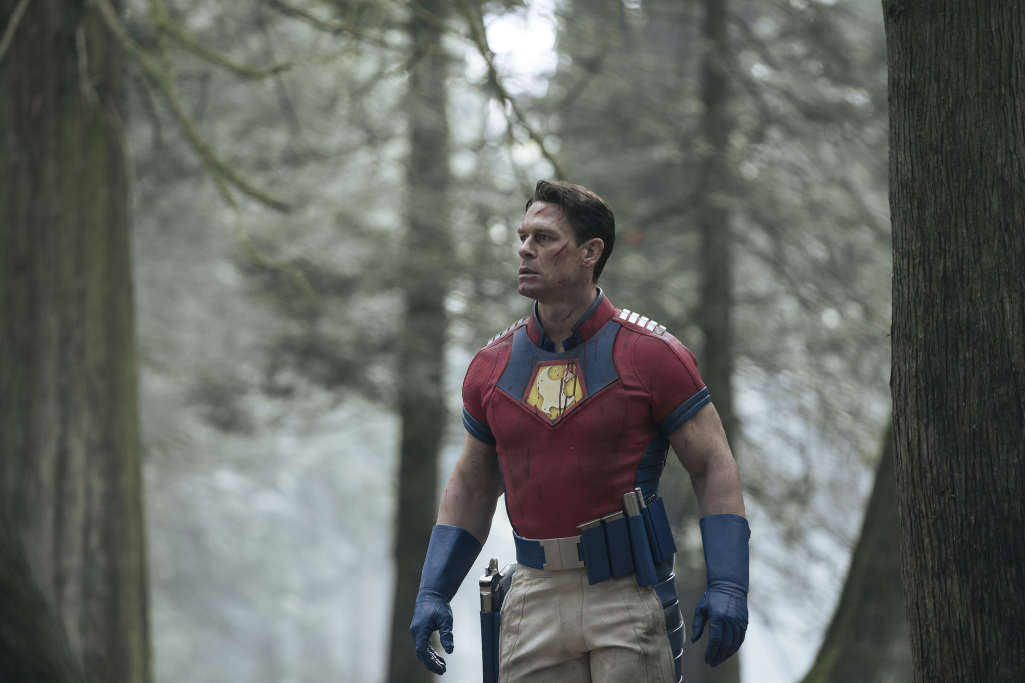 Le super-héros Peacemaker, tel que décrit par John Cena, marchant dans les bois.