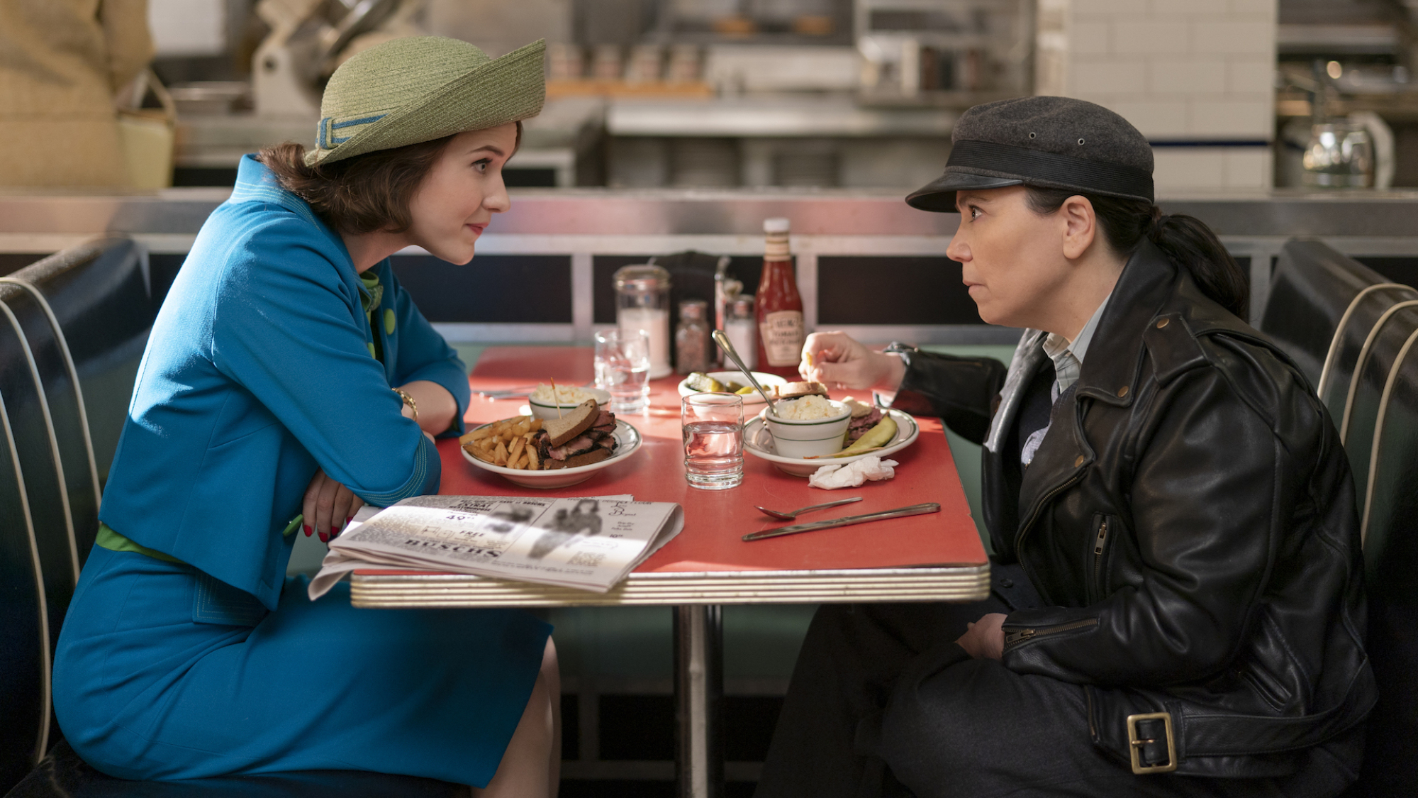 Deux femmes sont assises l'une en face de l'autre dans un restaurant des années 1950 ;  Rachel Brosnahan et Alex Borstein dans 