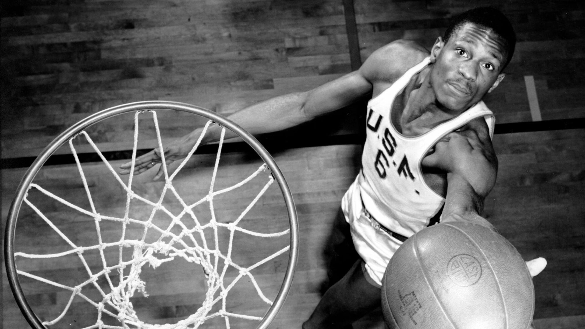 Bill Russell, membre de l'équipe de basket-ball de l'Université de San Francisco, montre comment il marque des paniers le 23 février 1956. Le centre de 6 pieds 10 pouces, classé parmi les meilleurs, a aidé son équipe à remporter 20 matchs consécutifs au cours de la saison en cours.