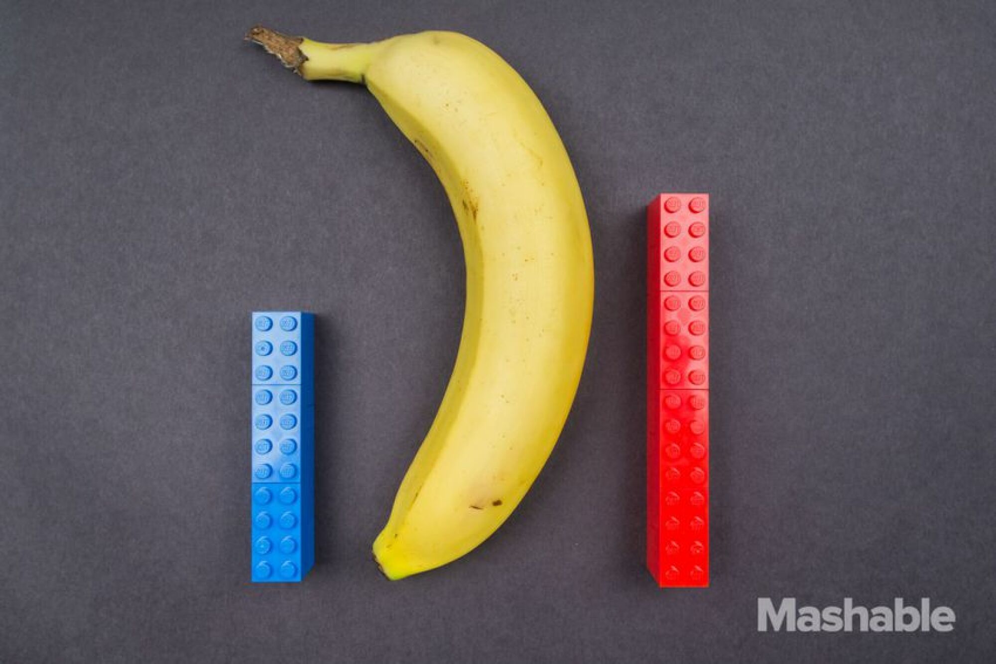 Les constructions Lego rouges et bleues à côté d'une banane.  Le lego bleu mesure environ la moitié de la longueur de la banane, tandis que le Lego rouge mesure environ les deux tiers de la longueur.