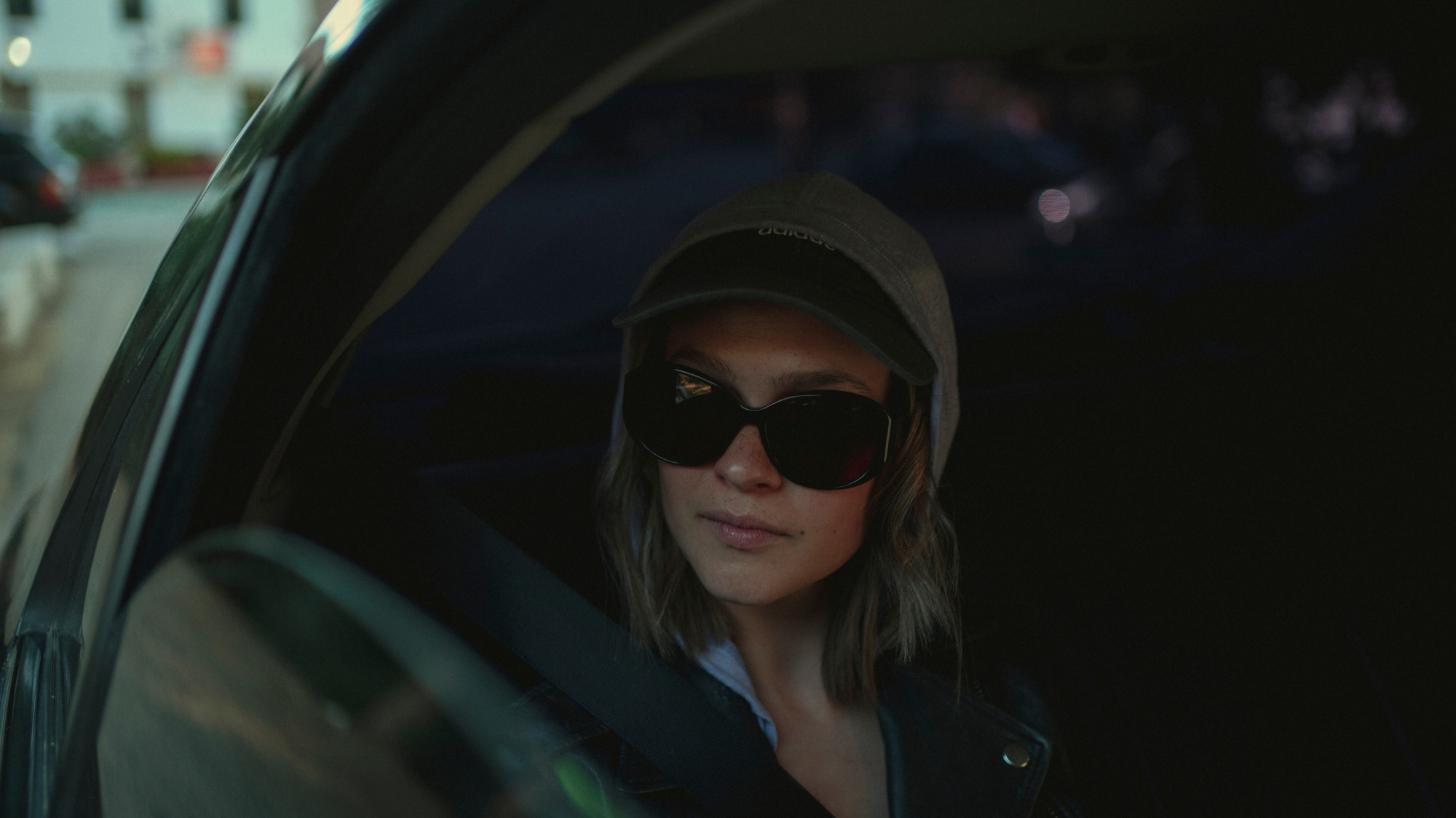 Une femme portant des lunettes de soleil regarde par une voiture dont les vitres sont baissées. 