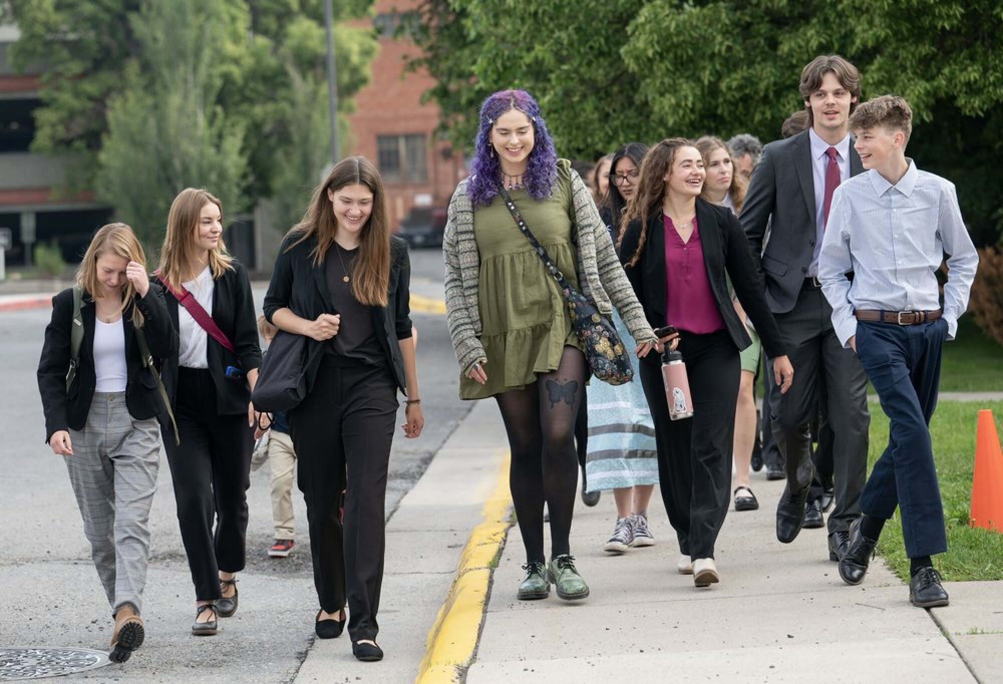 Un grand groupe de jeunes plaignants marchent dans une rue.