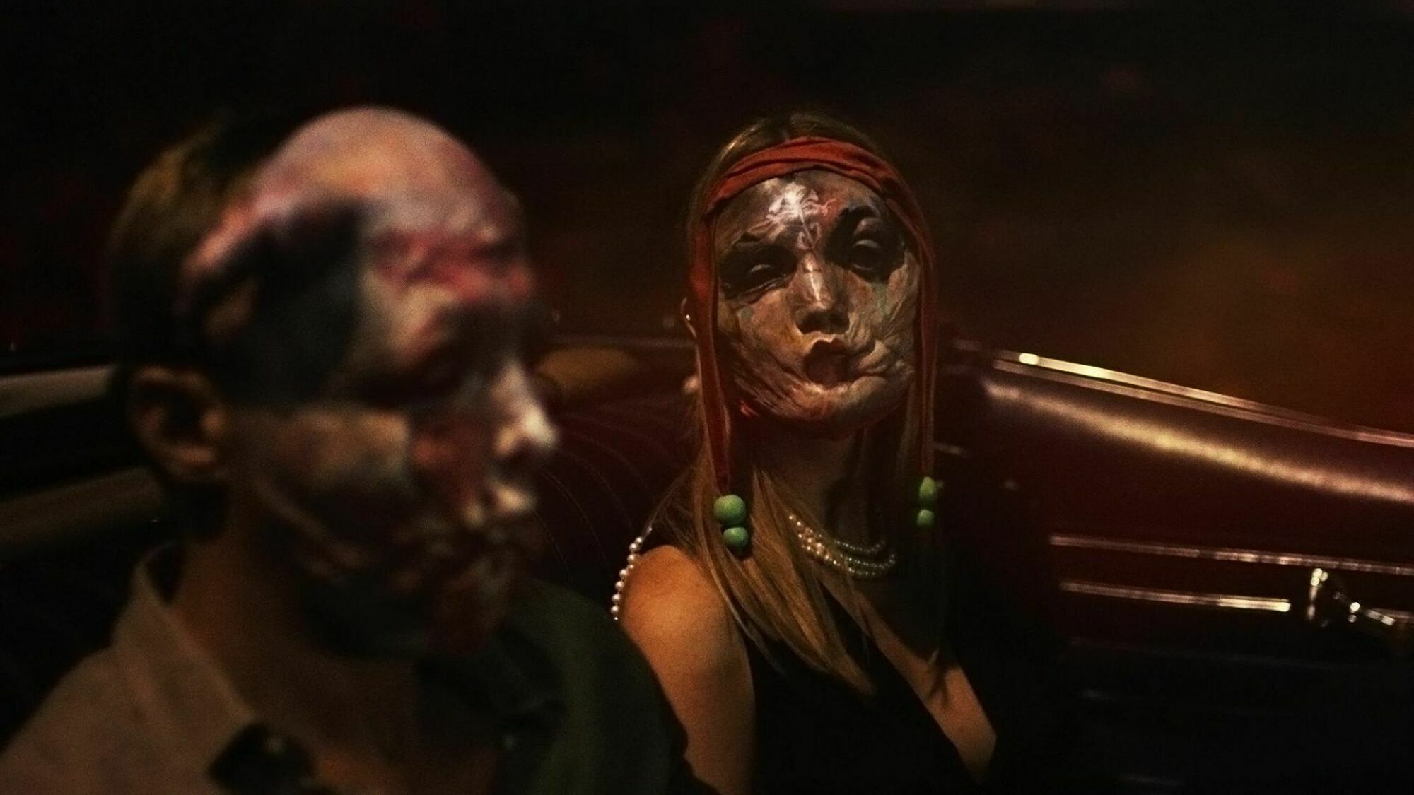 Deux personnes portant des masques effrayants sont assises dans une voiture. 