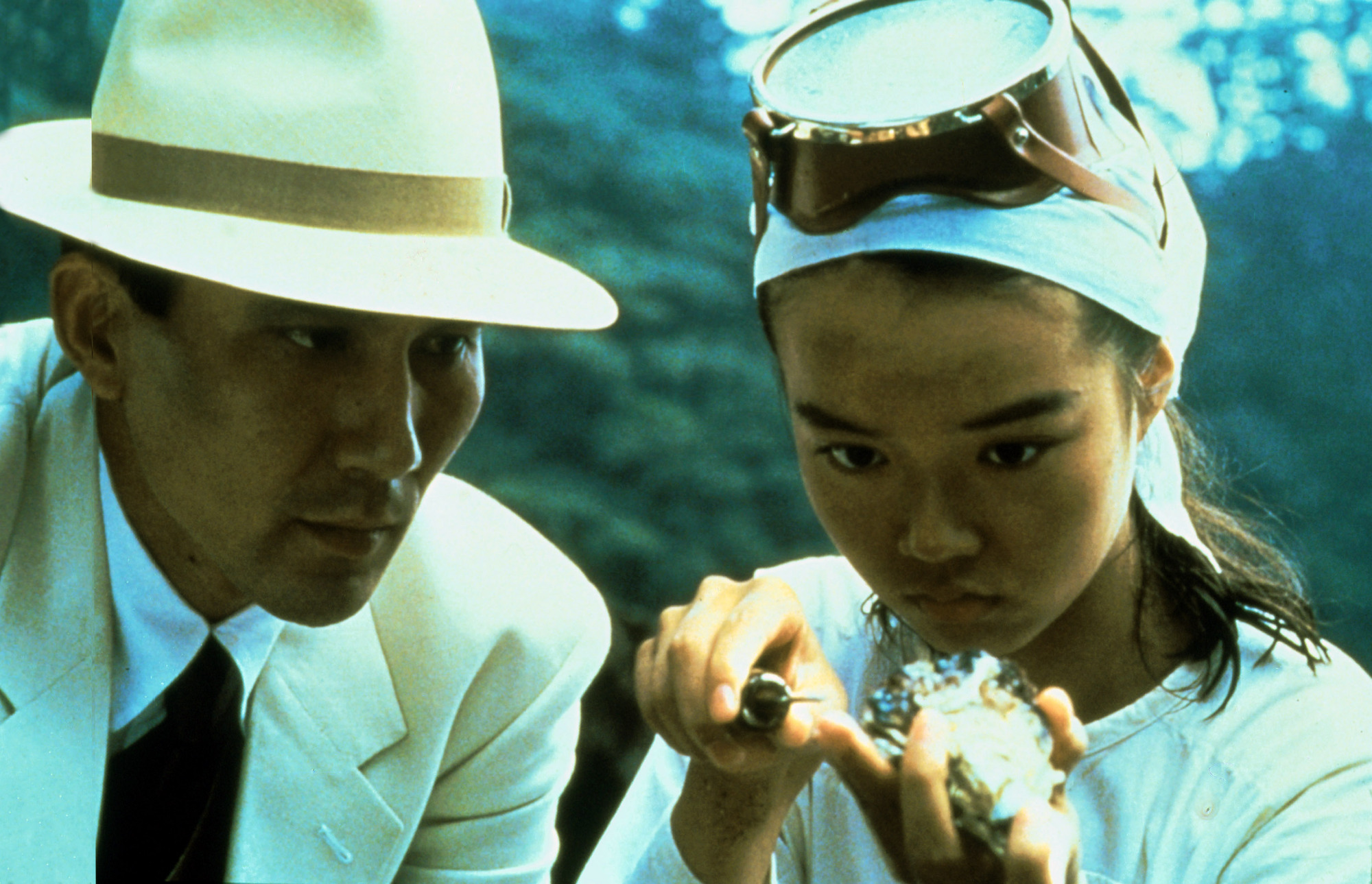 Un homme et une femme, tous deux vêtus de blanc, ouvrent un coquillage. 