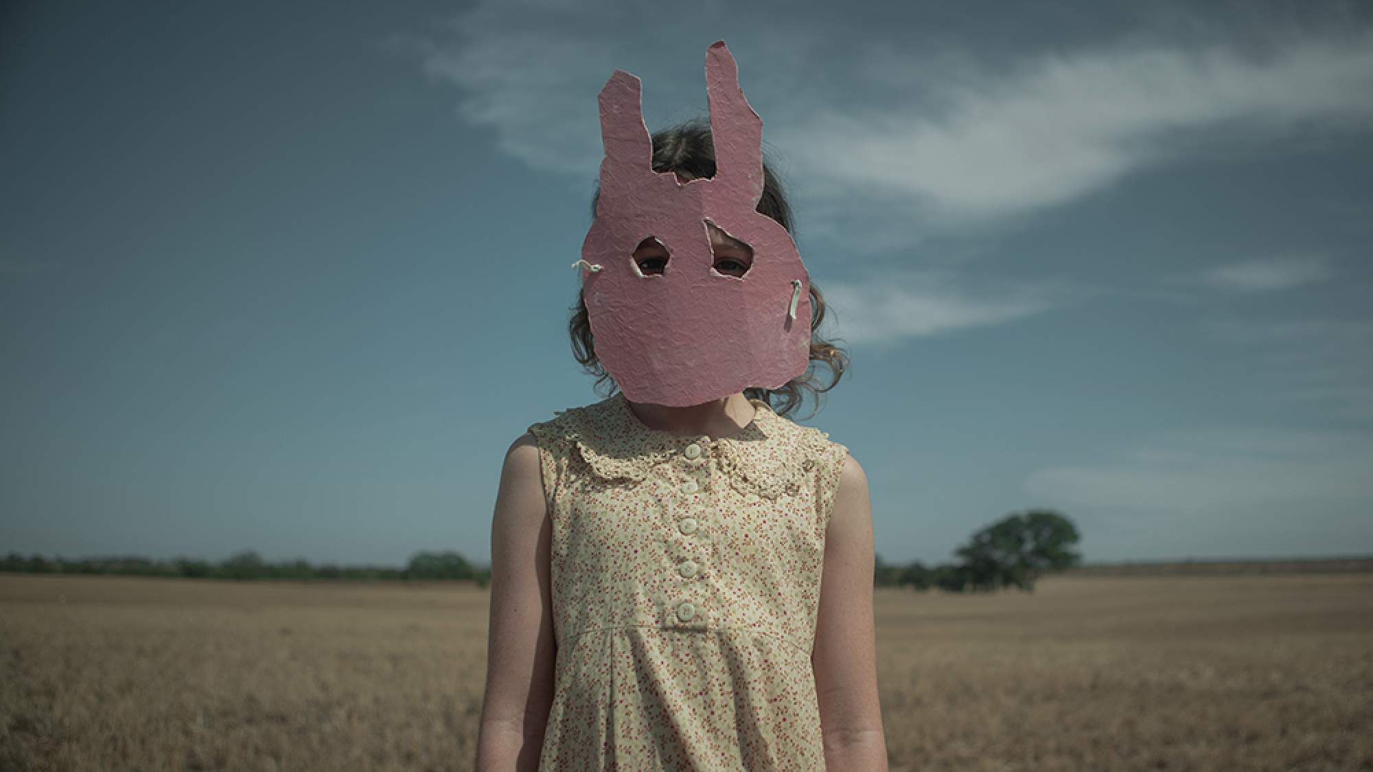 Une fille dans un masque de lapin rose se tient dans le désert.