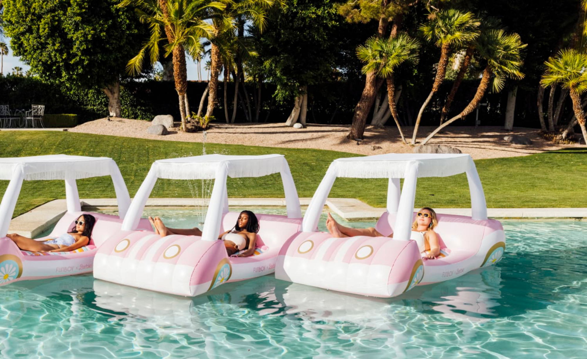Trois personnes dans une voiturette de golf sur le thème de Barbie flottent dans la piscine avec des palmiers en arrière-plan