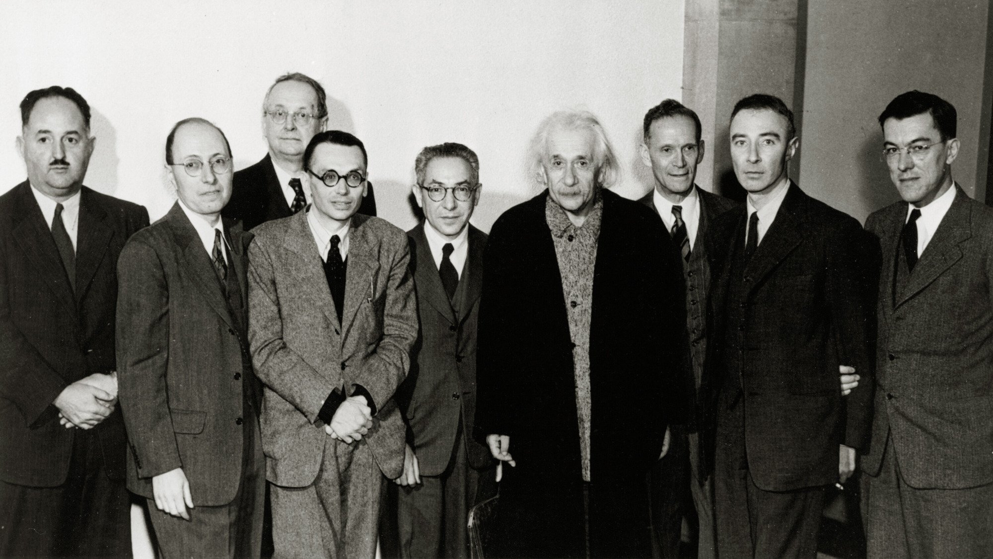 Une photo en noir et blanc d'Albert Einstein entouré de collègues. 