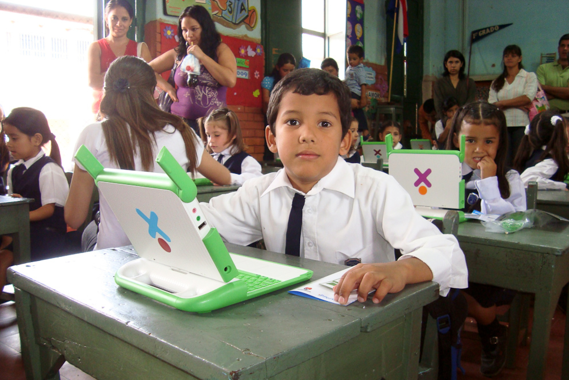 Des enfants assis dans une salle de classe, utilisant des ordinateurs portables XO.