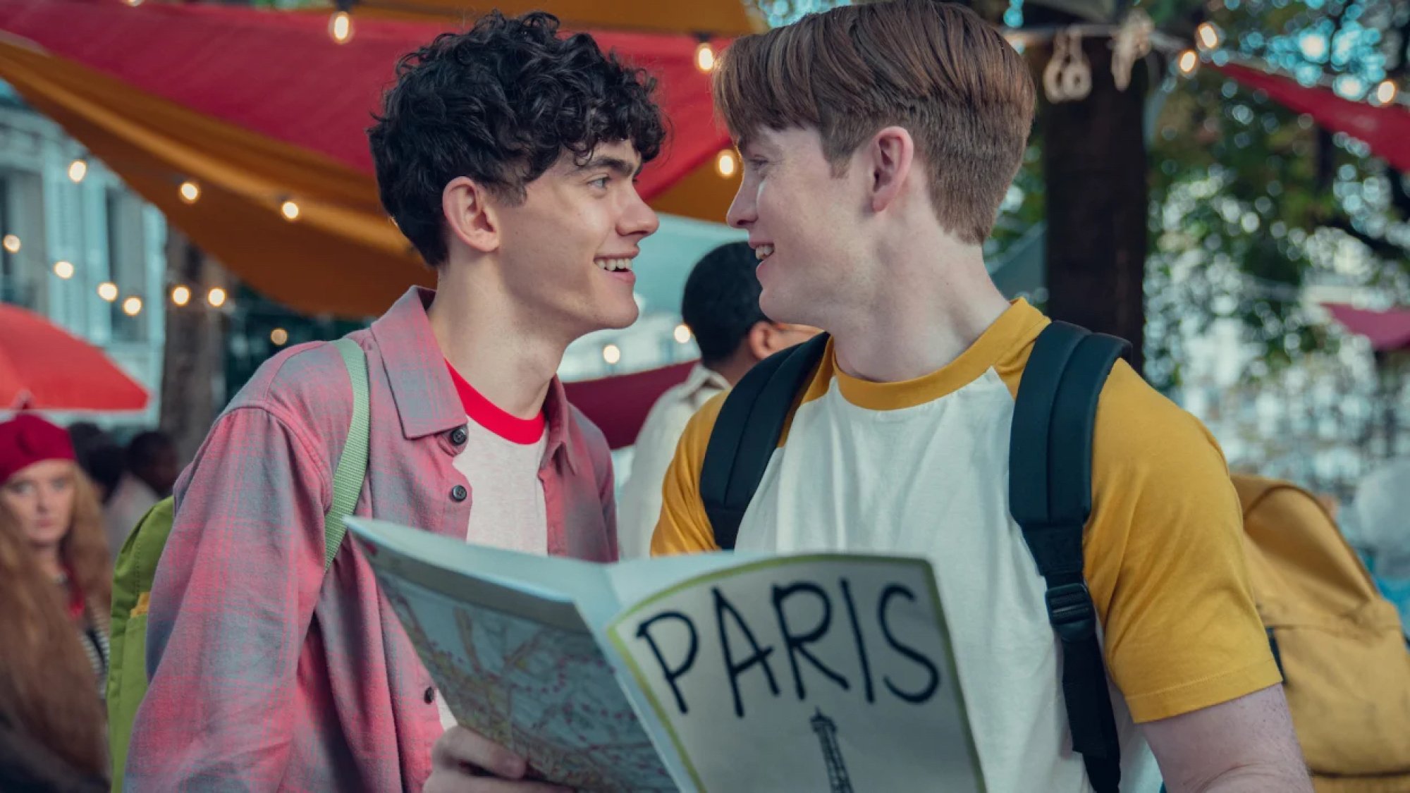 Deux adolescents se regardent amoureusement en tenant une brochure touristique sur Paris.