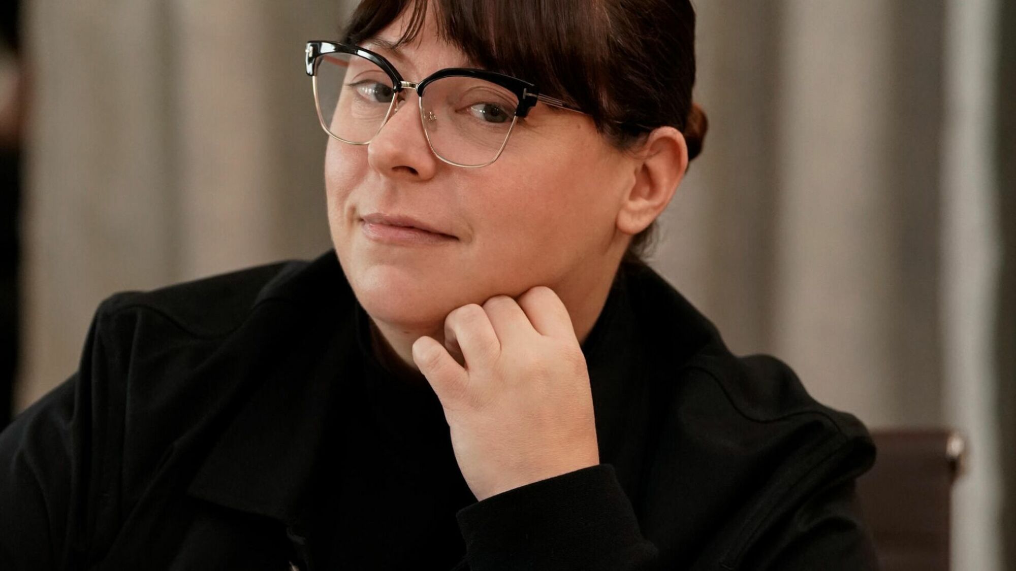 Une femme portant des lunettes et une veste noire. 