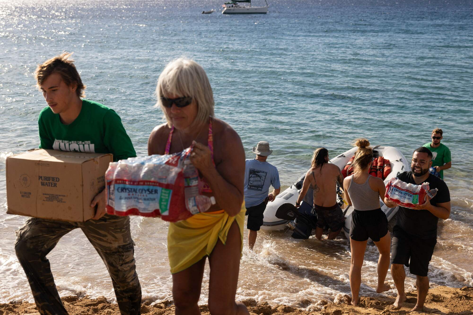 Les gens tirent de l'eau et des fournitures d'un petit radeau sur une plage,