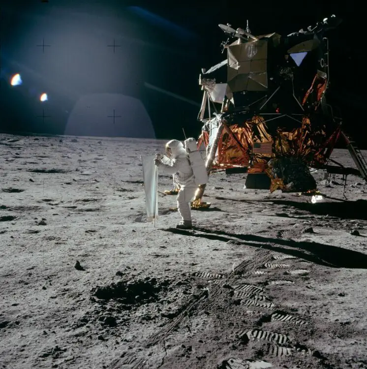 Une photo prise le 20 juillet 1969 par l'astronaute d'Apollo 11 Neil Armstrong, le premier à marcher sur la Lune.  Sur la photo, le module lunaire de la mission, l'Eagle, et le pilote du module lunaire en combinaison spatiale Buzz Aldrin déployant une longue feuille de papier d'aluminium également connue sous le nom d'expérience de composition du vent solaire. 