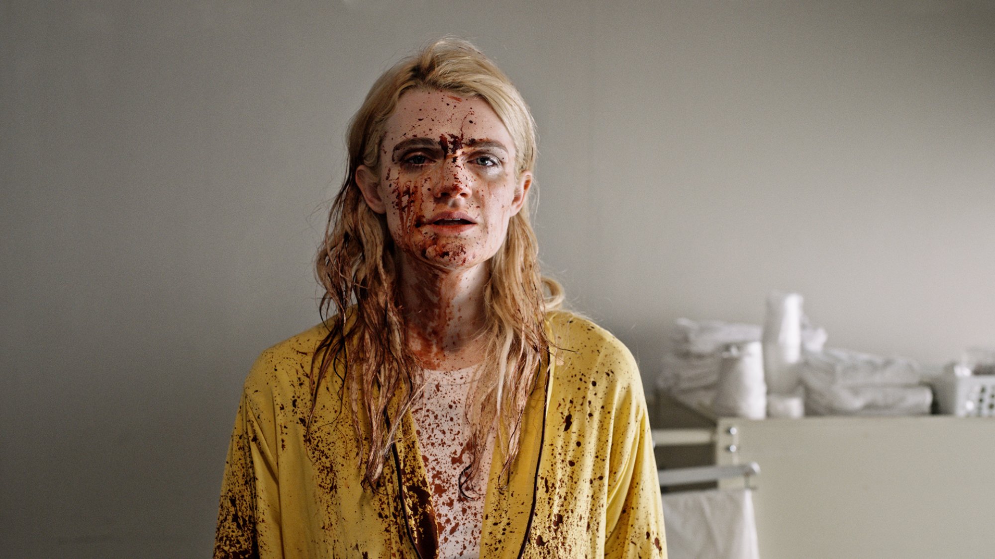 Une femme se tient dans une pièce couverte d'éclaboussures de sang.