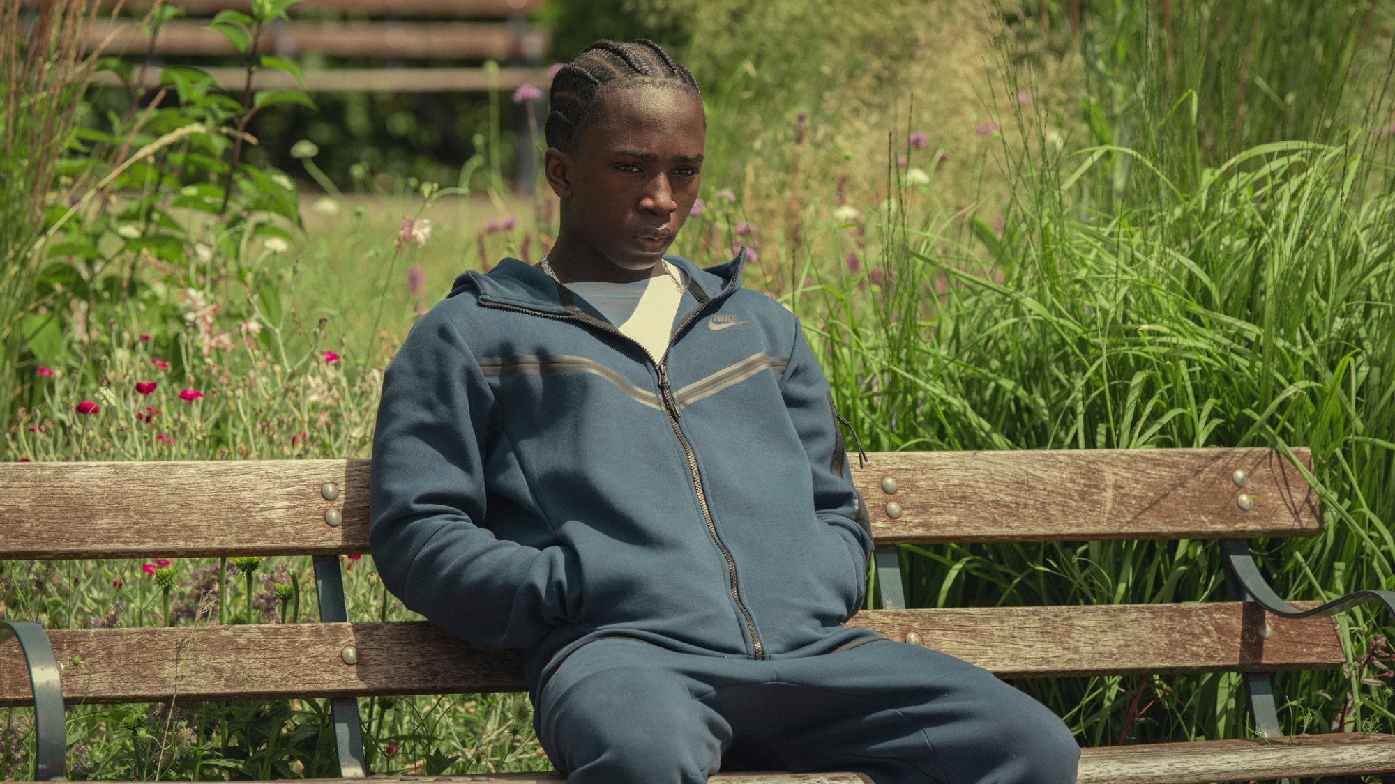 Araloyin Oshunremi dans le rôle de Stef, assis sur un banc de parc, l