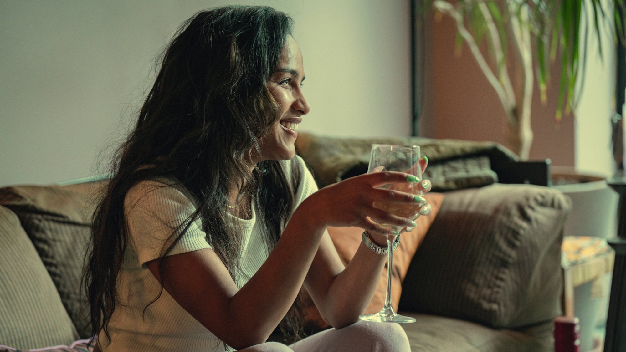 Saffron Hocking dans le rôle de Lauryn, assise sur le canapé avec un verre de vin dans la saison 3 de "Top Boy"