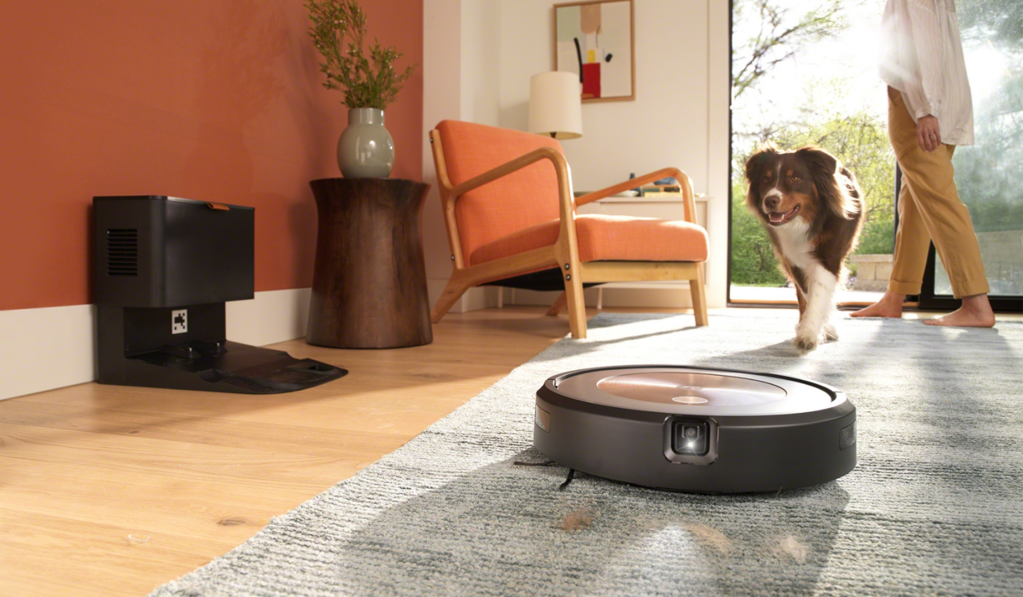 Roomba avec appareil photo et tapis de nettoyage des phares avec station d'accueil, chien et personne en arrière-plan