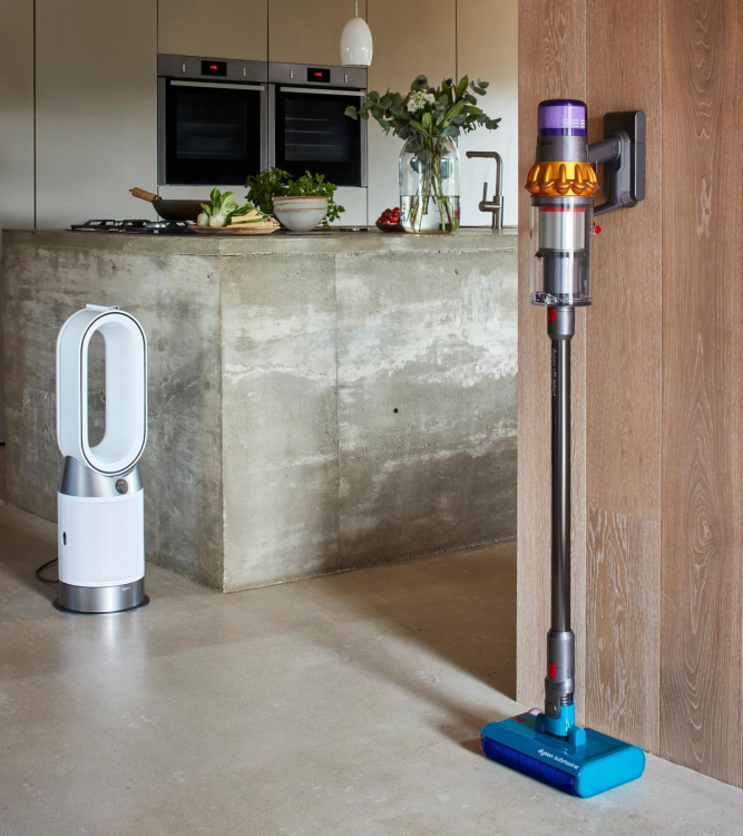 Aspirateur sans fil Dyson et vadrouille contre le mur avec cuisine et ventilateur Dyson en arrière-plan