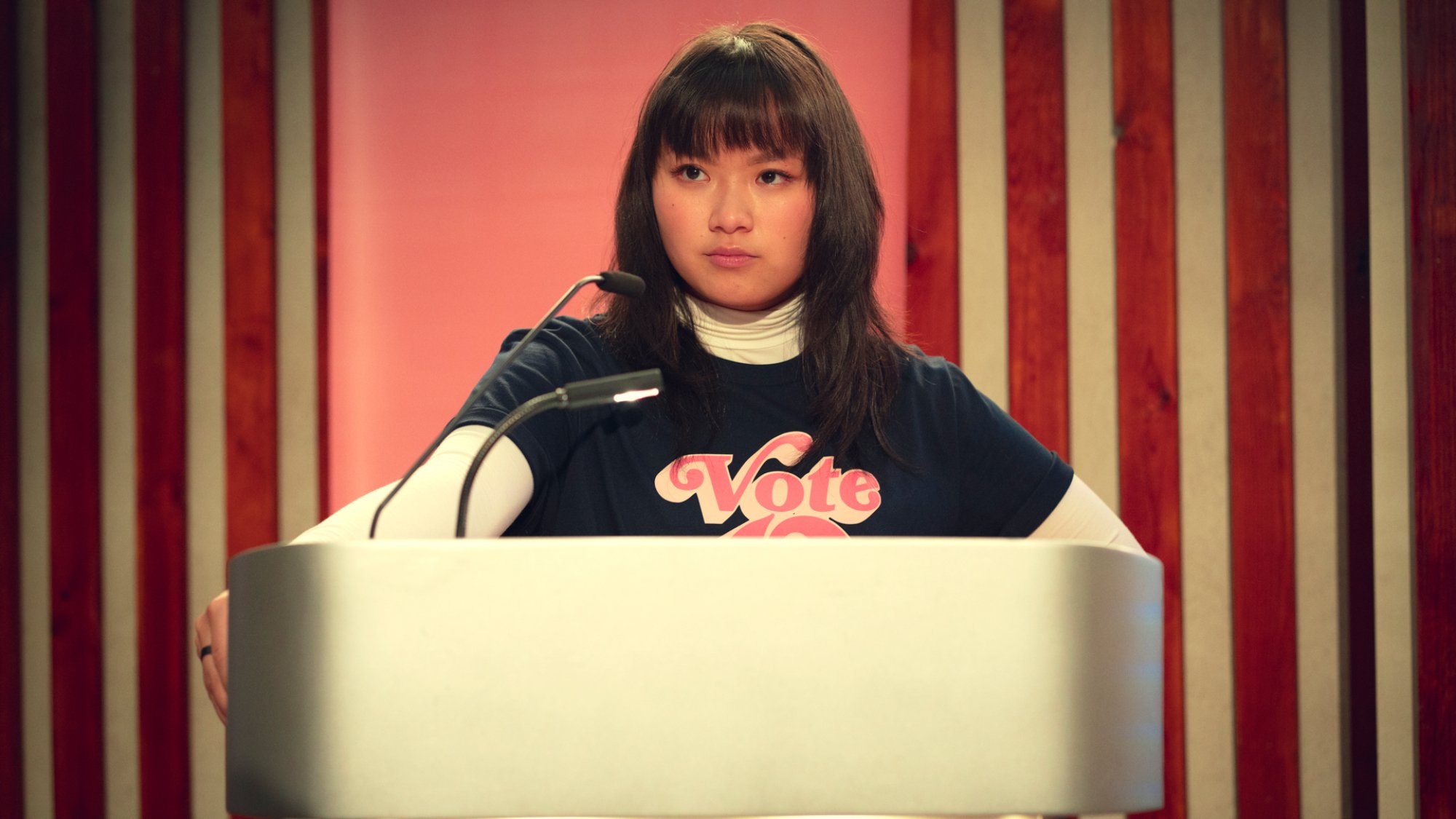 Un étudiant adolescent se tient derrière un pupitre pour prononcer un discours de campagne.