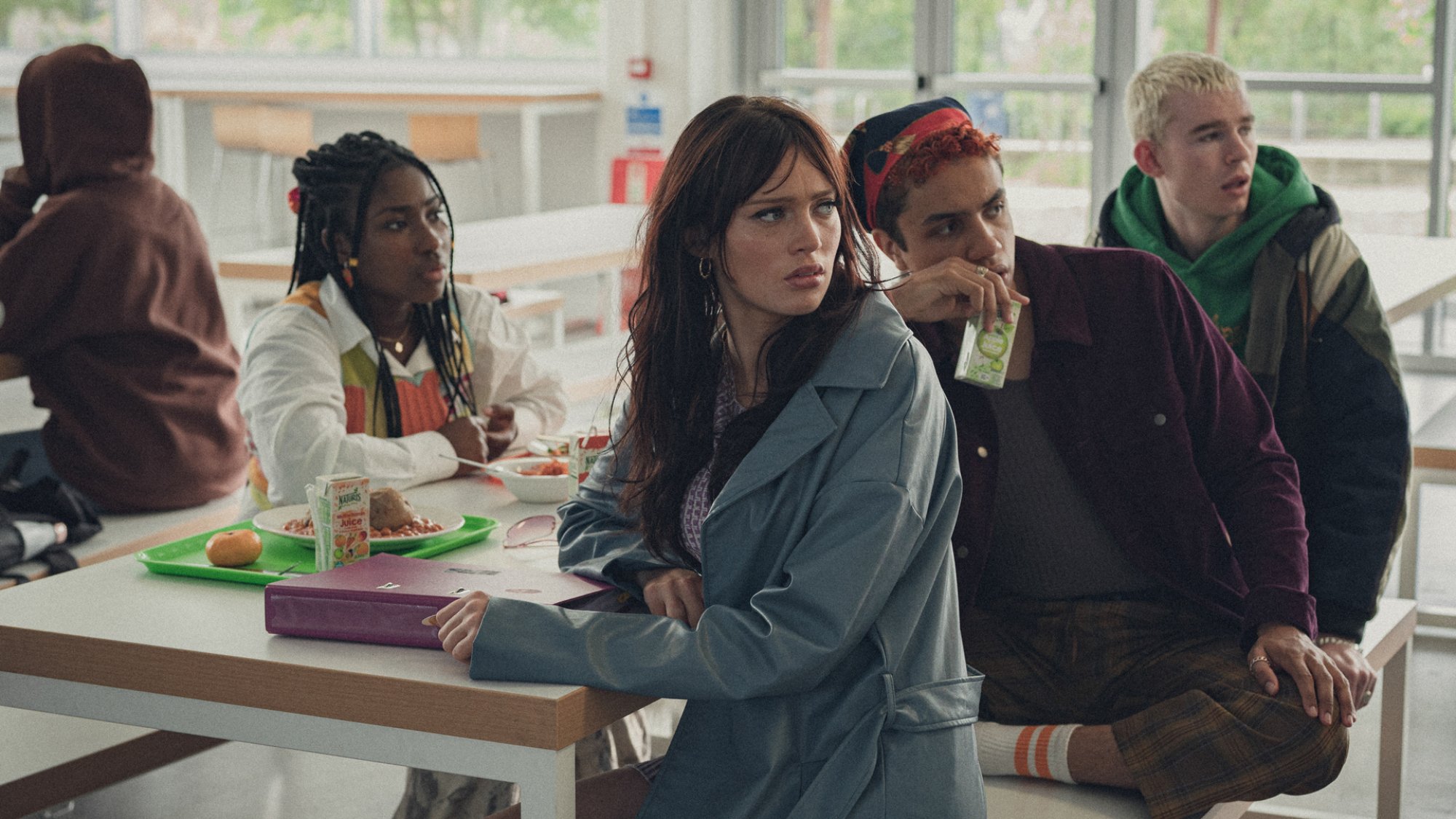 Un groupe d’adolescents est assis à une table de cafétéria et semble inquiet.