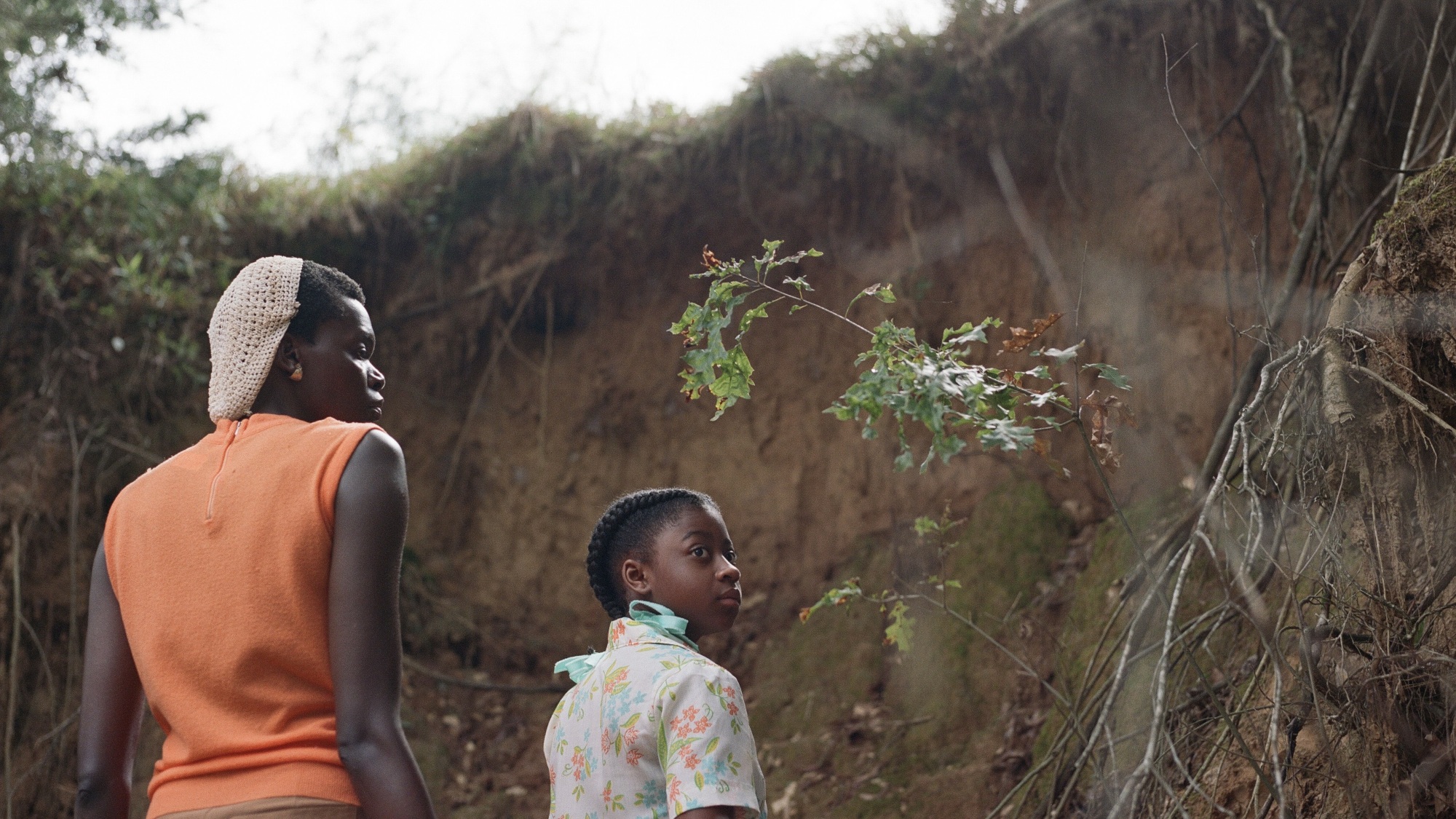 Une femme et sa fille regardent une colline de terre argileuse.