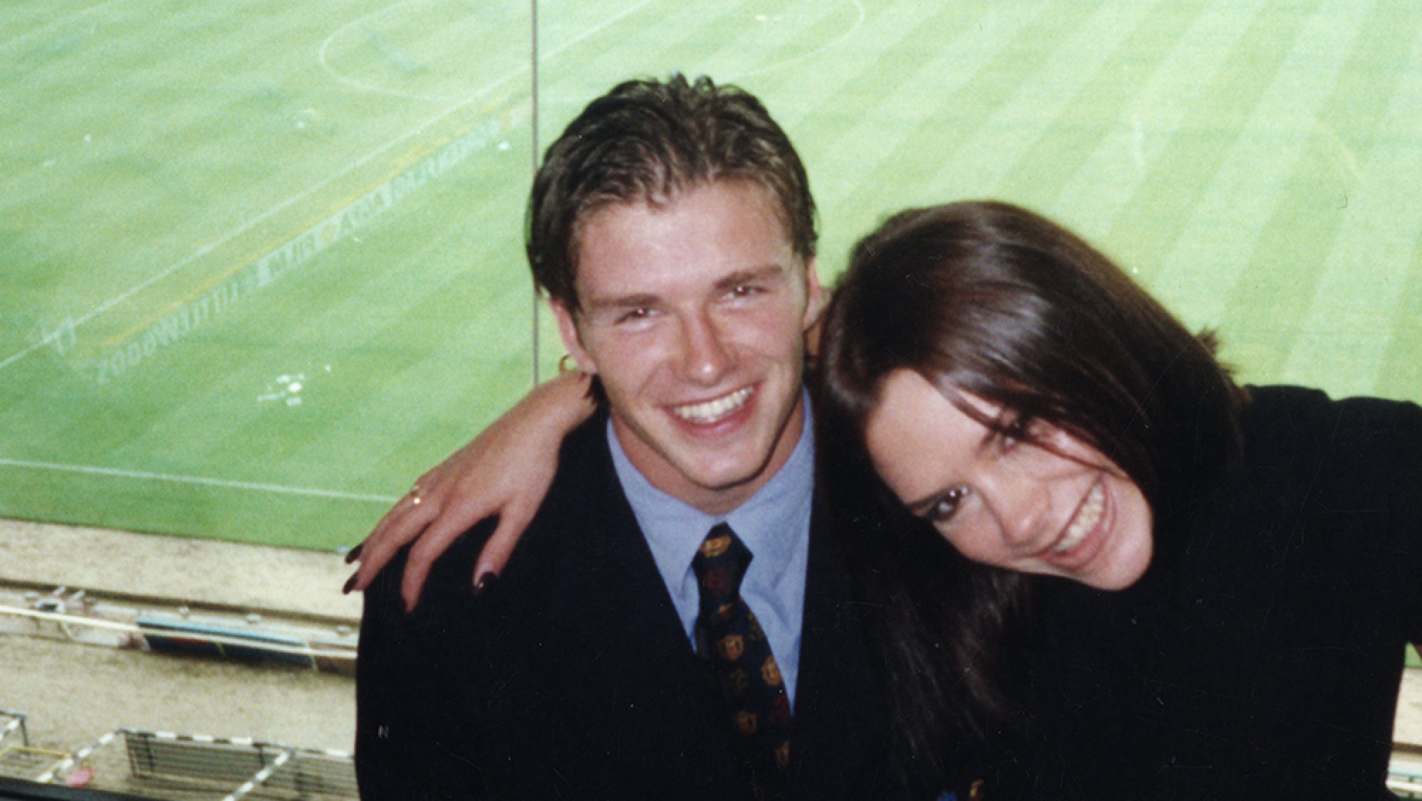 Un homme et une femme sourient dans les tribunes d’un stade de football.