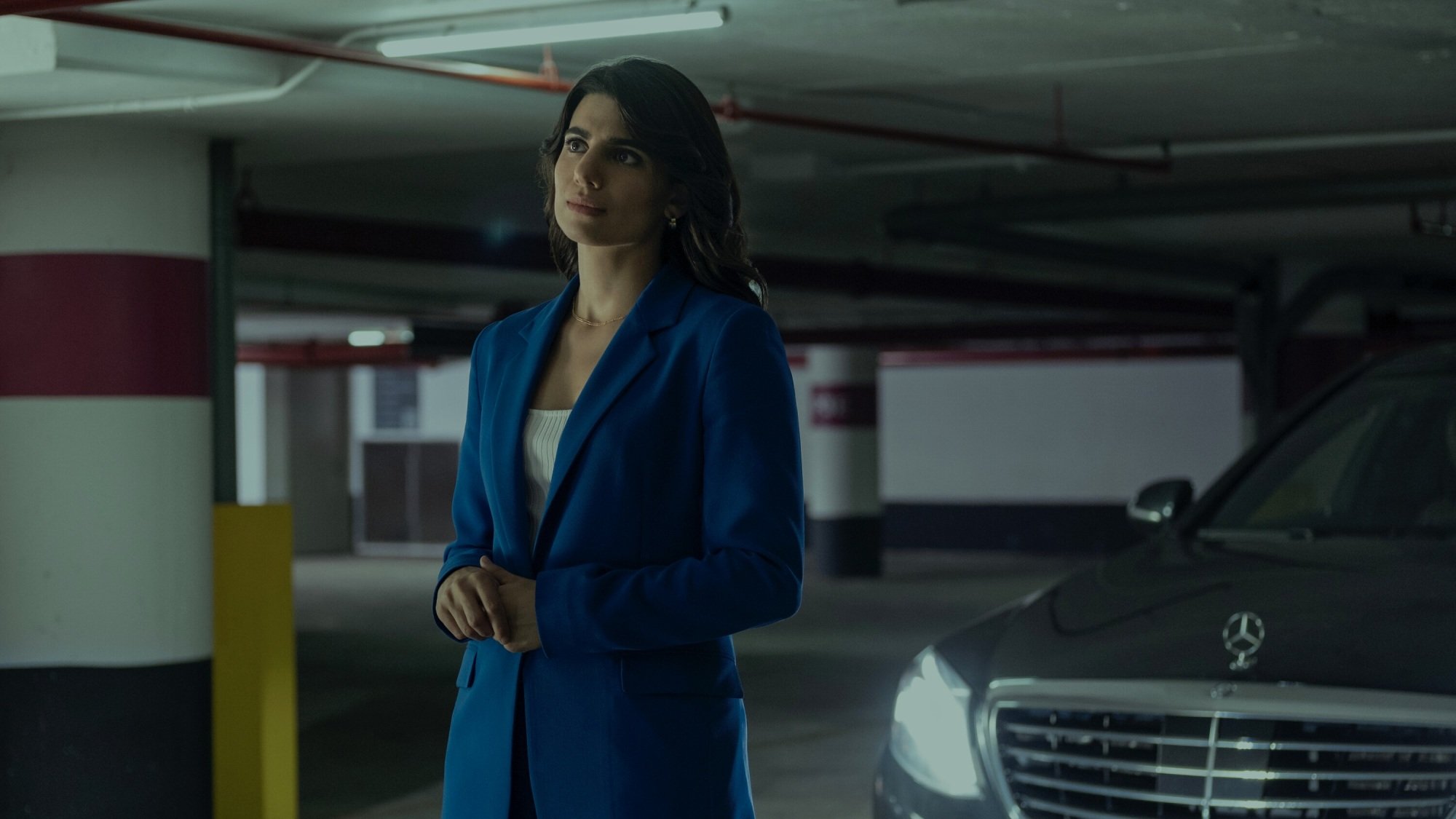 Une femme en costume bleu debout dans un parking.