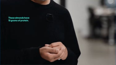 Vidéo de démonstration originale de Humane Ai Pin, gros plan du co-fondateur Imran Chaudhri tenant une poignée d'amandes, avec un texte indiquant qu'ils contiennent 15 grammes de protéines. 