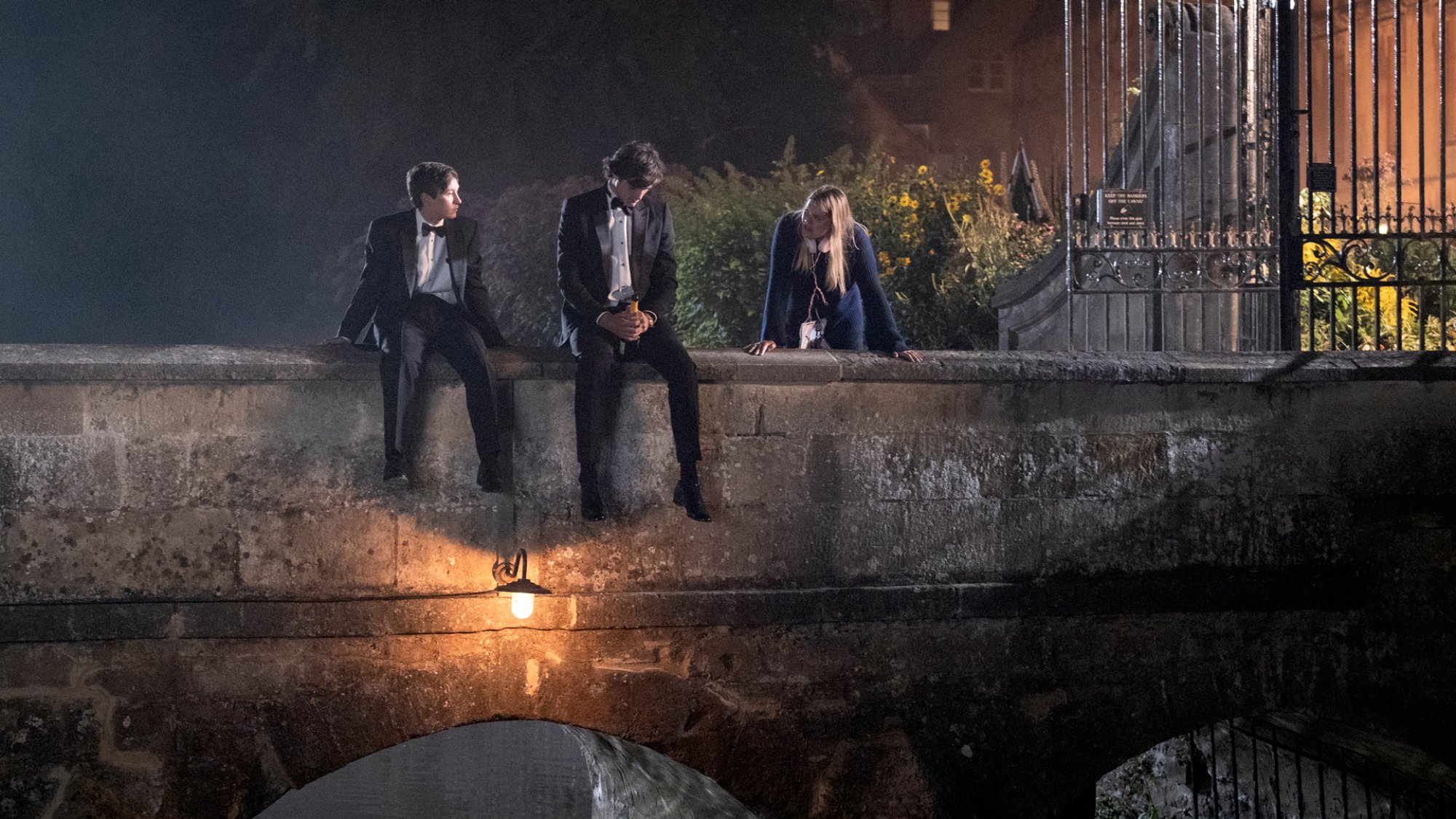 Deux garçons en smoking sont assis sur un vieux pont de pierre. 