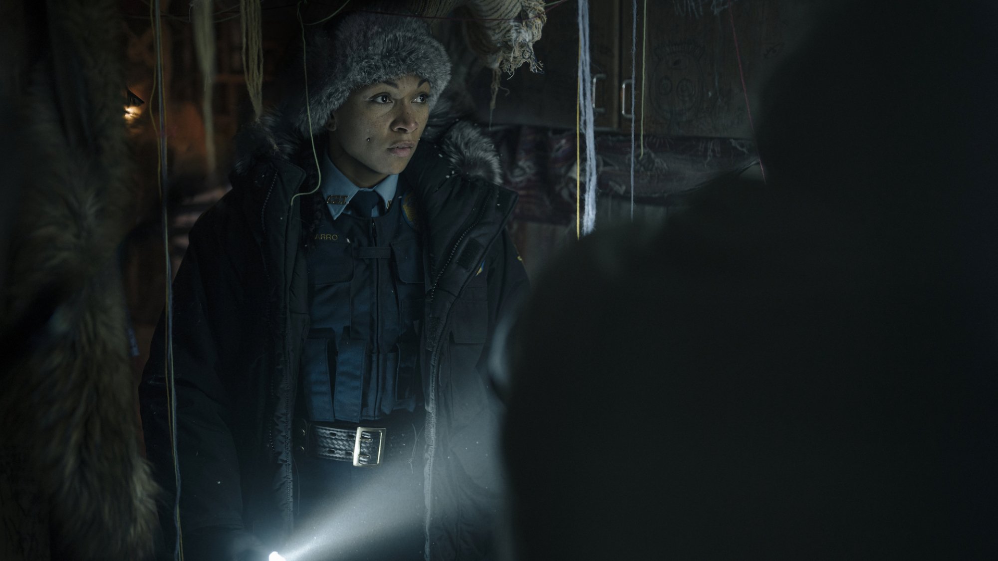 Un policier d'État se promène dans un espace sombre avec une lampe de poche.