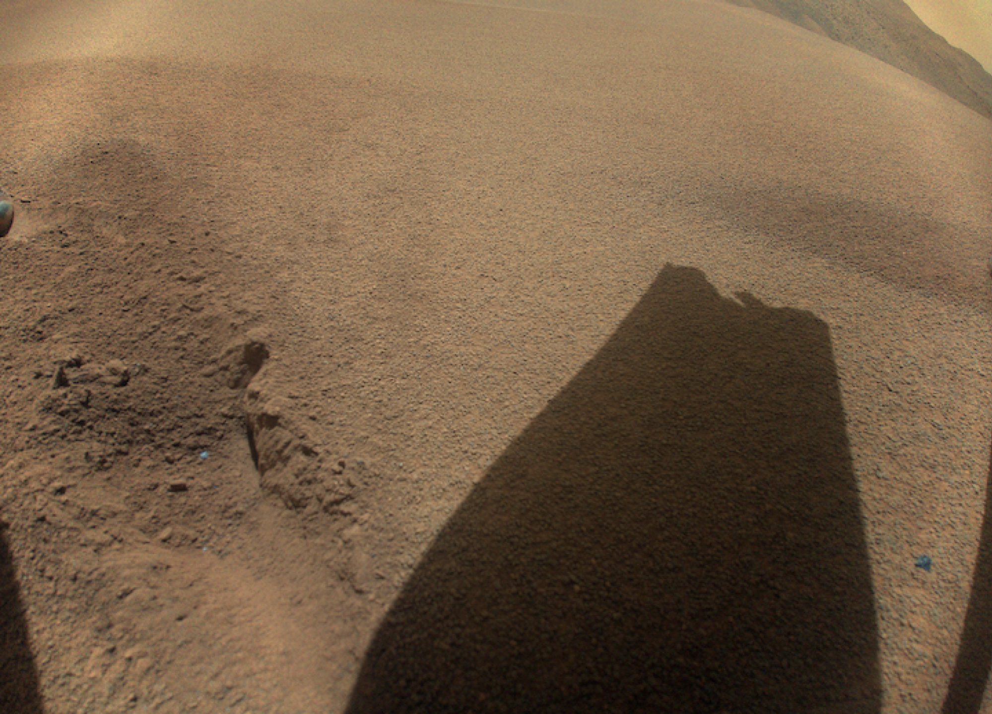 L’ombre d’une pointe de rotor Ingenuity cassée projetée sur le sol martien.