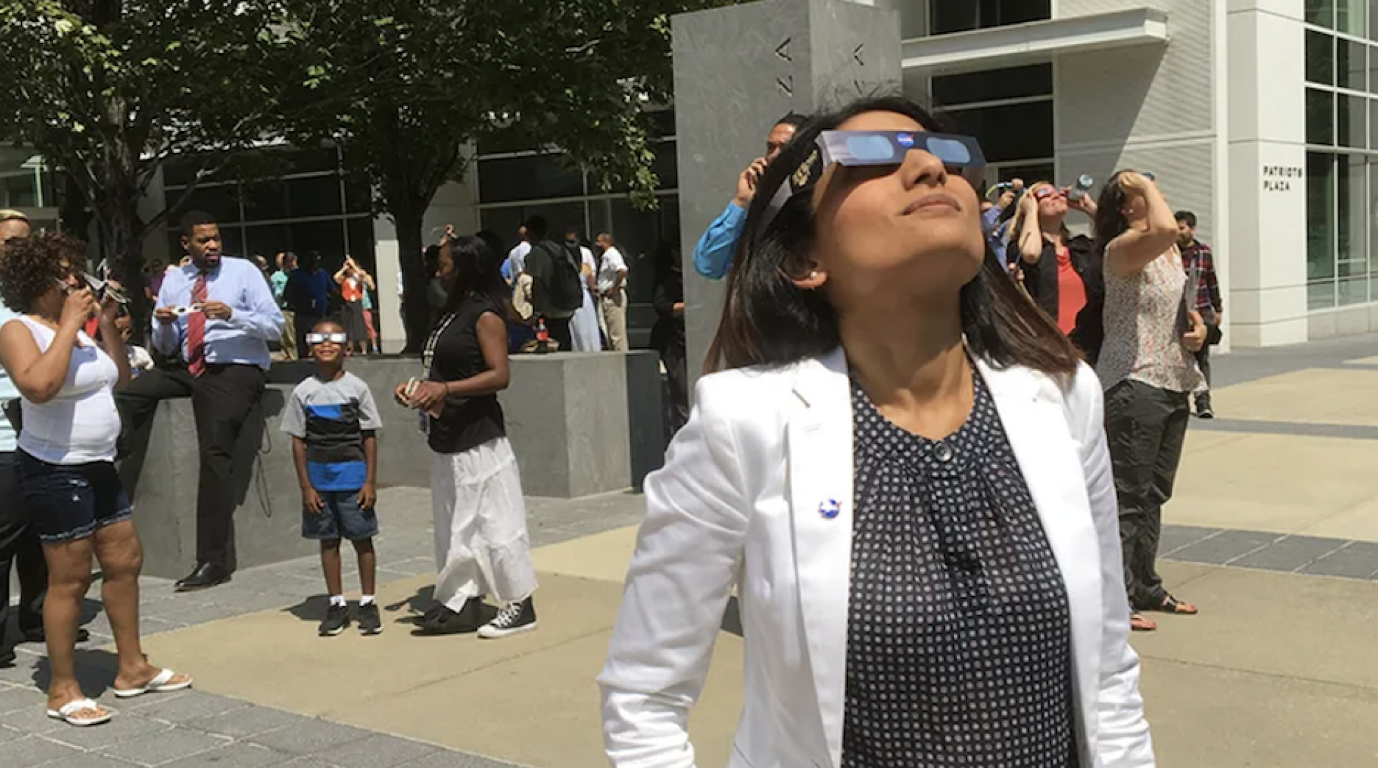 Une femme regarde l’éclipse avec des lunettes à éclipse.