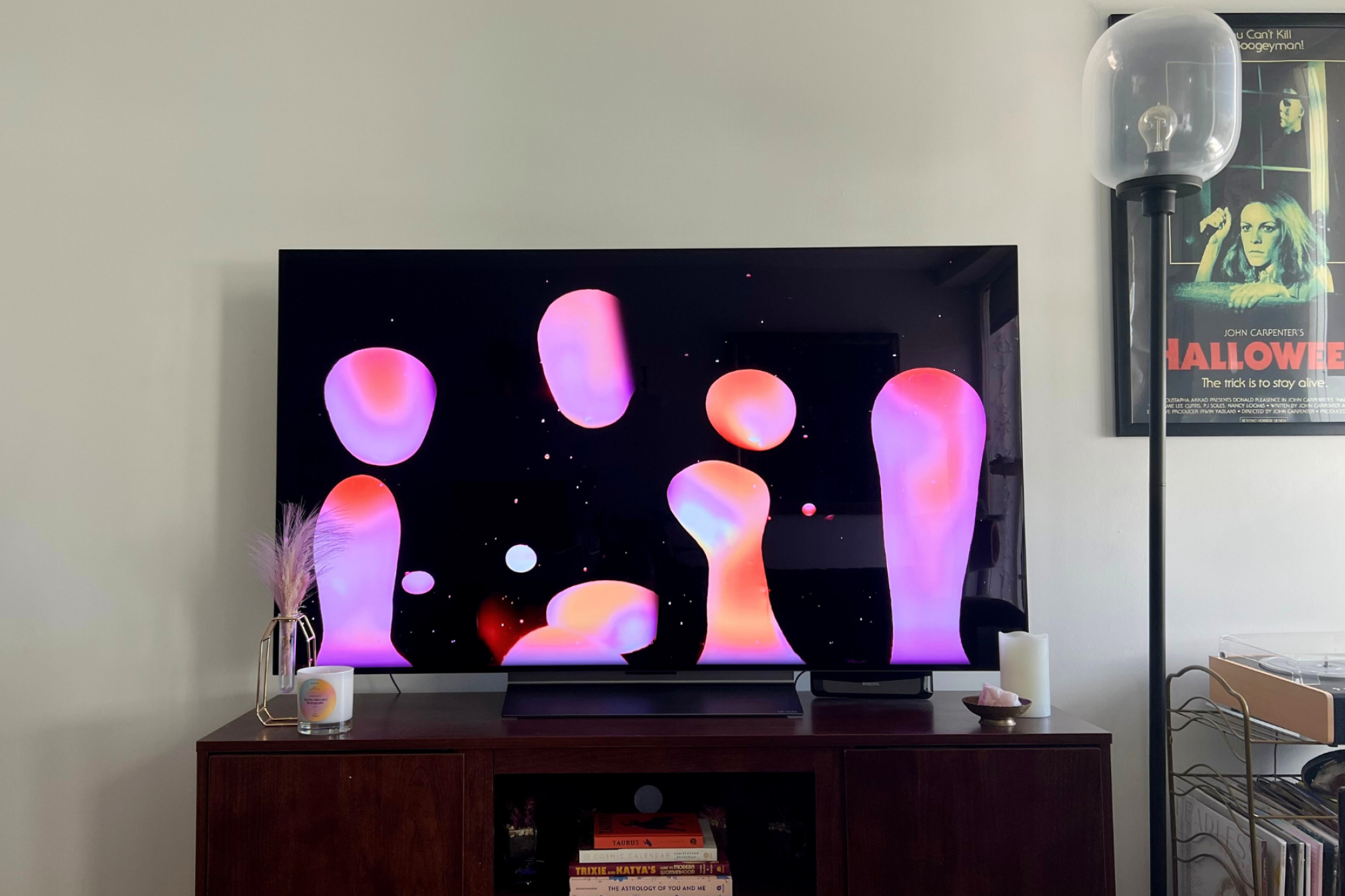 Téléviseur LG C3 avec économiseur d'écran lampe à lave posé sur un meuble TV avec lampe dans un coin