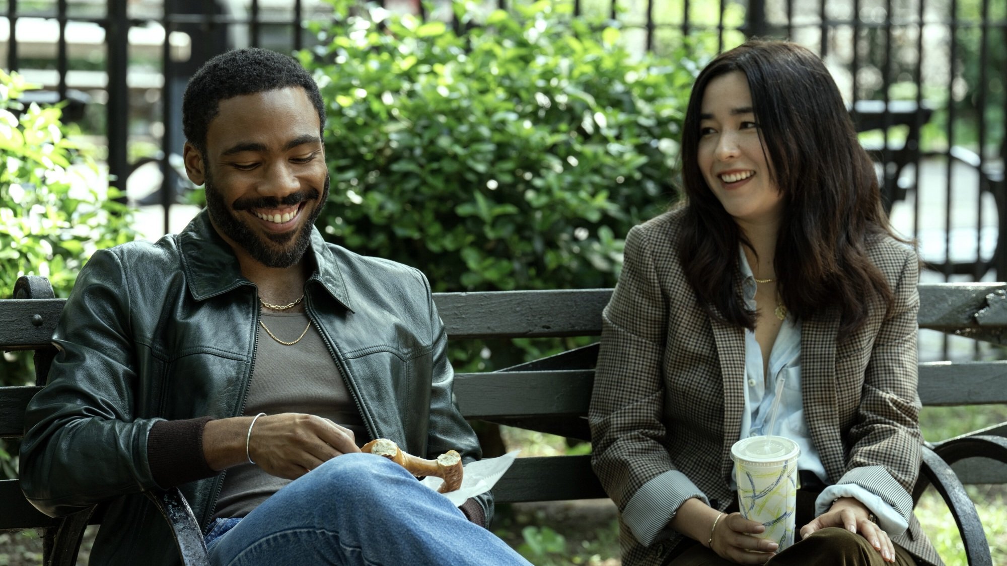 Un homme et une femme rient ensemble sur un banc de parc.