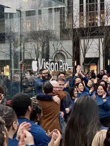 Tim Cook embrasse un homme vêtu d'une veste marron devant l'Apple Store.