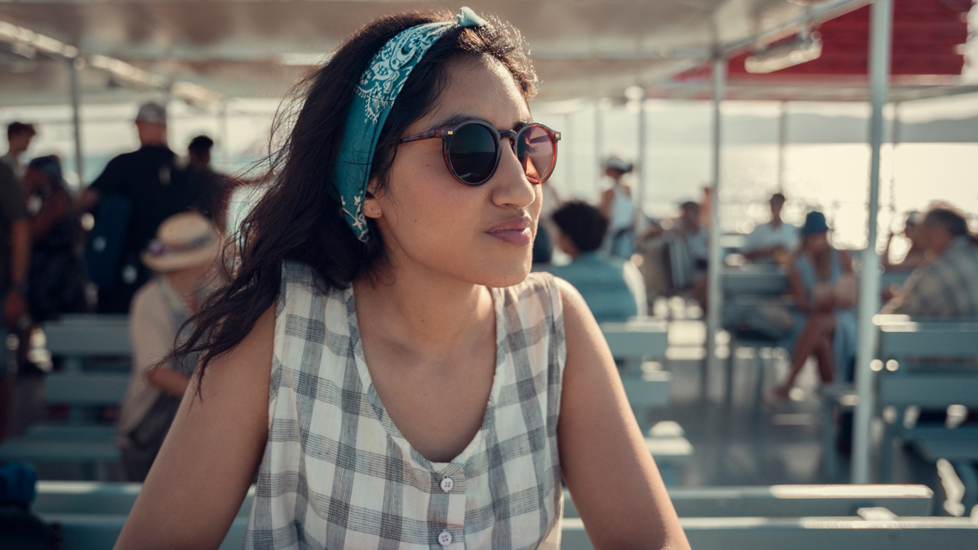 Une jeune femme portant des lunettes de soleil est assise au soleil sur un ferry.