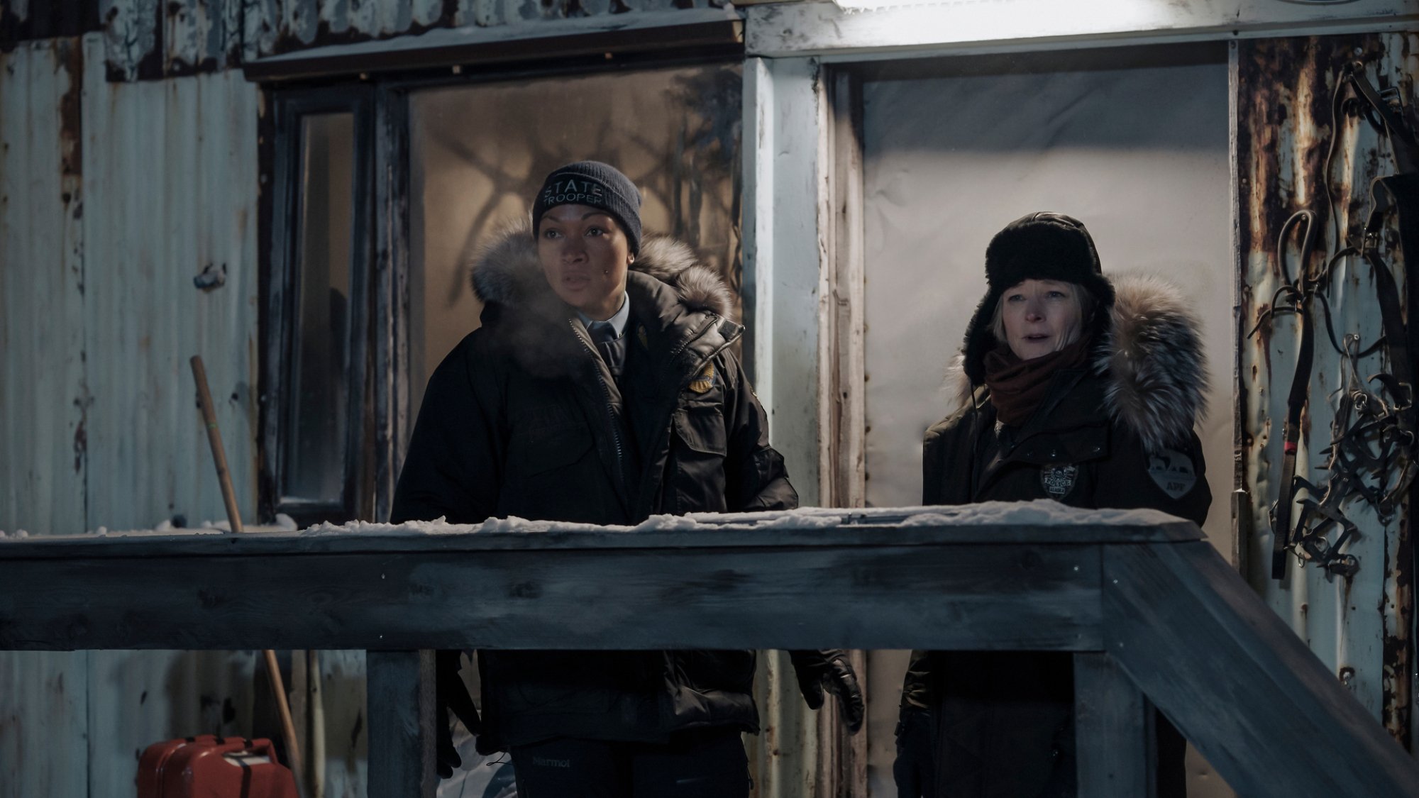 La chef de la police Liz Danvers (Jodie Foster) et la policière Evangeline Siqiññaatchiaq Navarro (Kali Reis) se tiennent devant une maison délabrée.