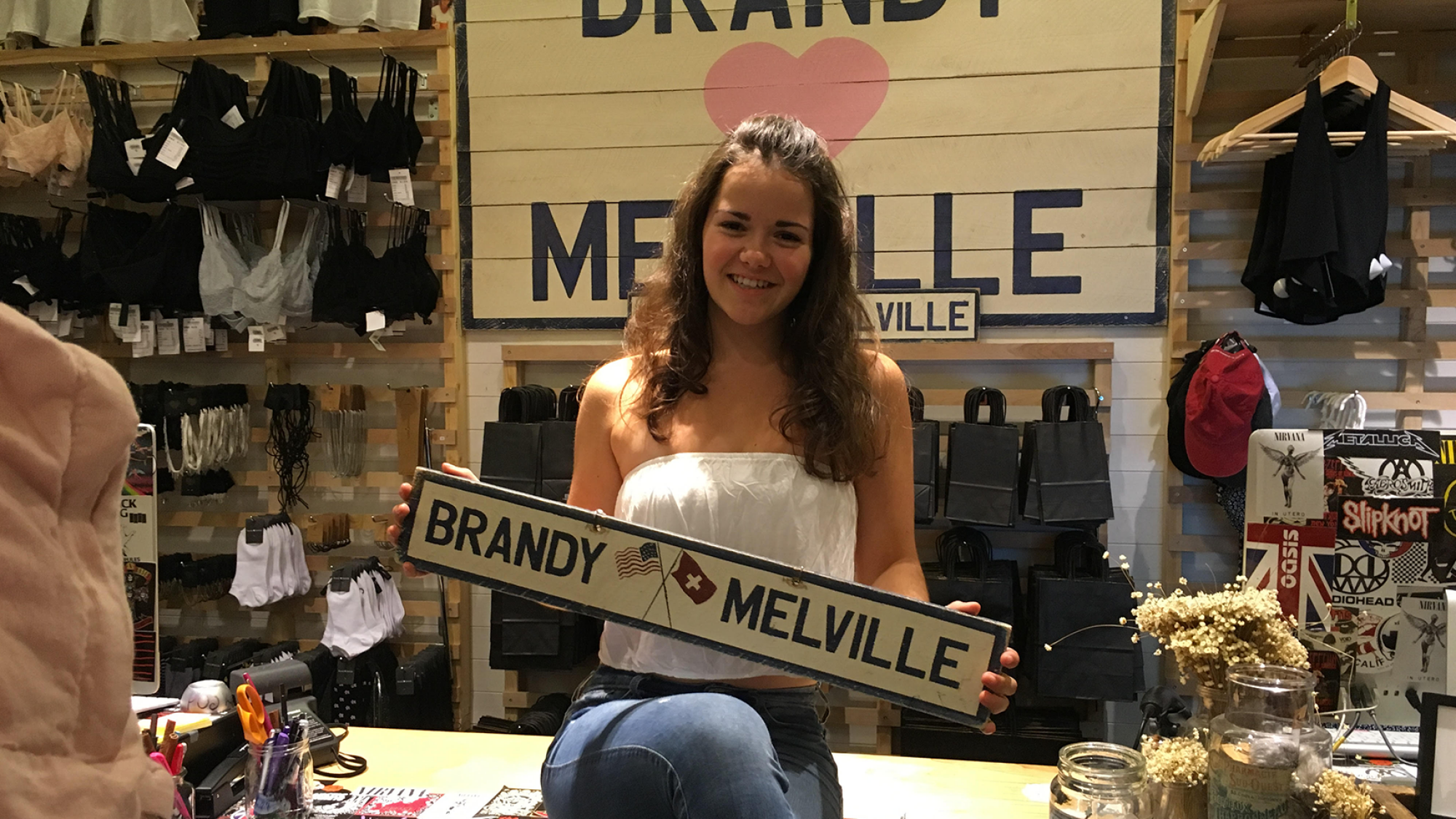 Une adolescente pose avec une pancarte Brandy Melville dans le magasin titulaire.