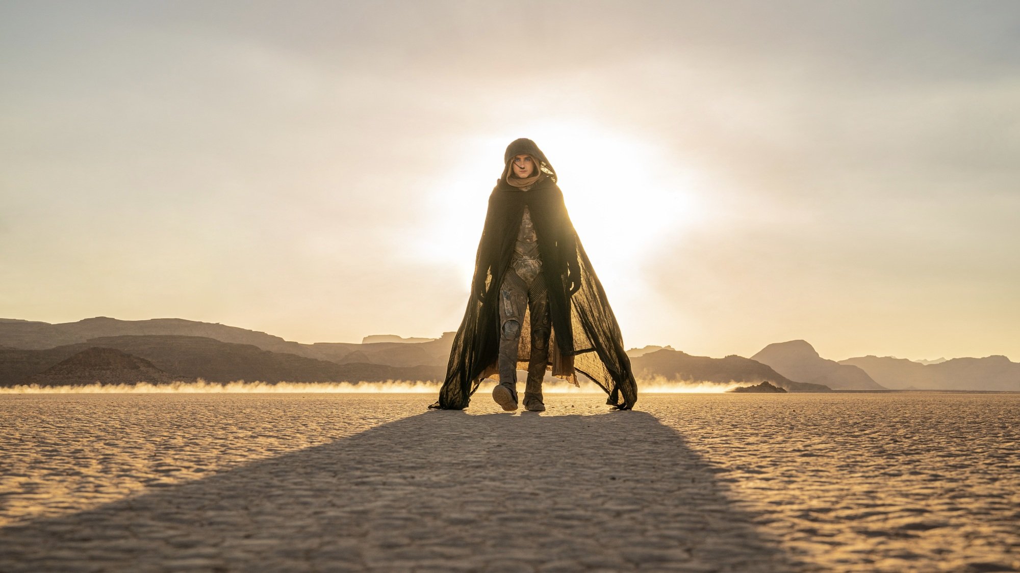 Paul Atreides se promène dans le désert, le soleil dans le dos, vêtu d'un immobile et d'une cape Fremen.