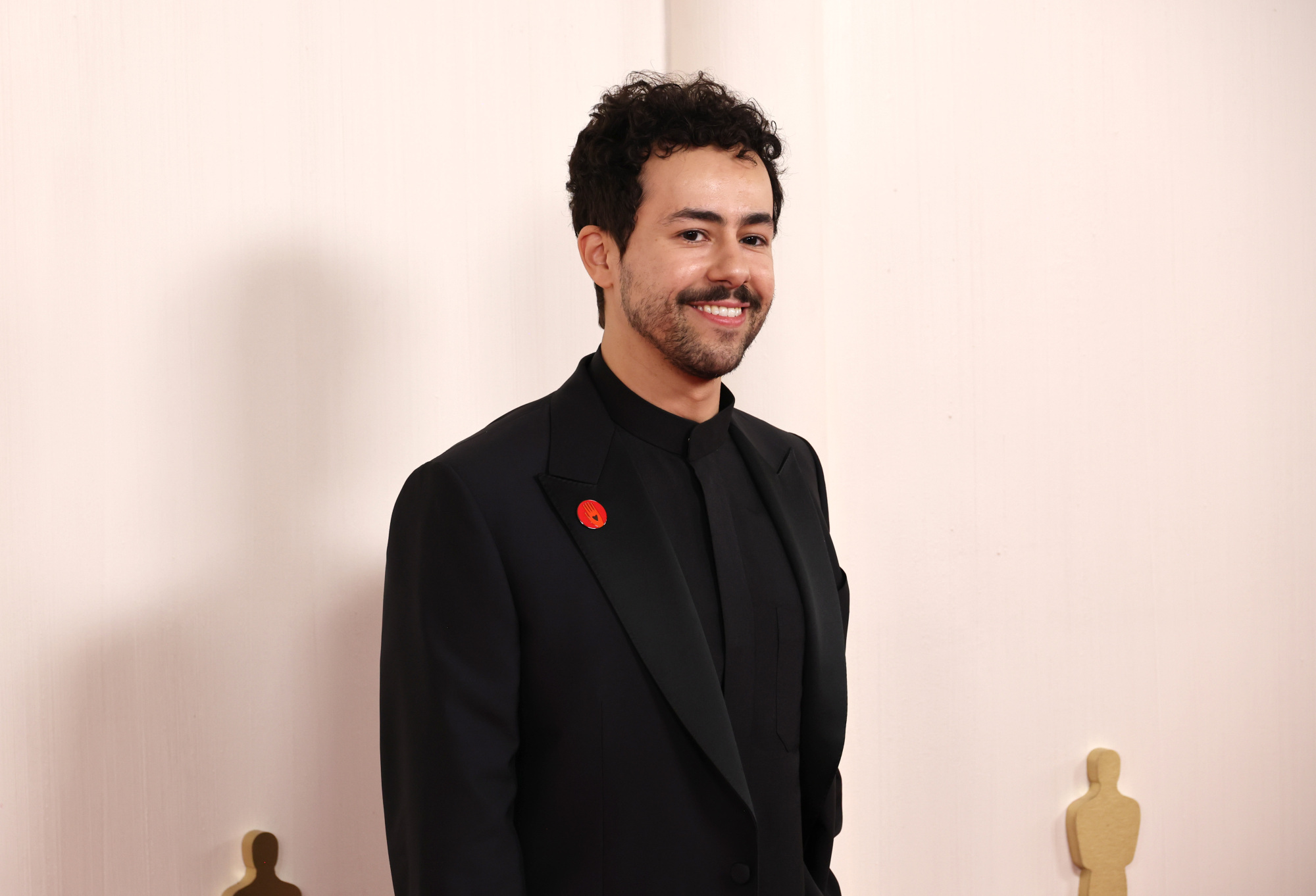 Ramy Youssef portant le pin's rouge Artists For Ceasefire.
