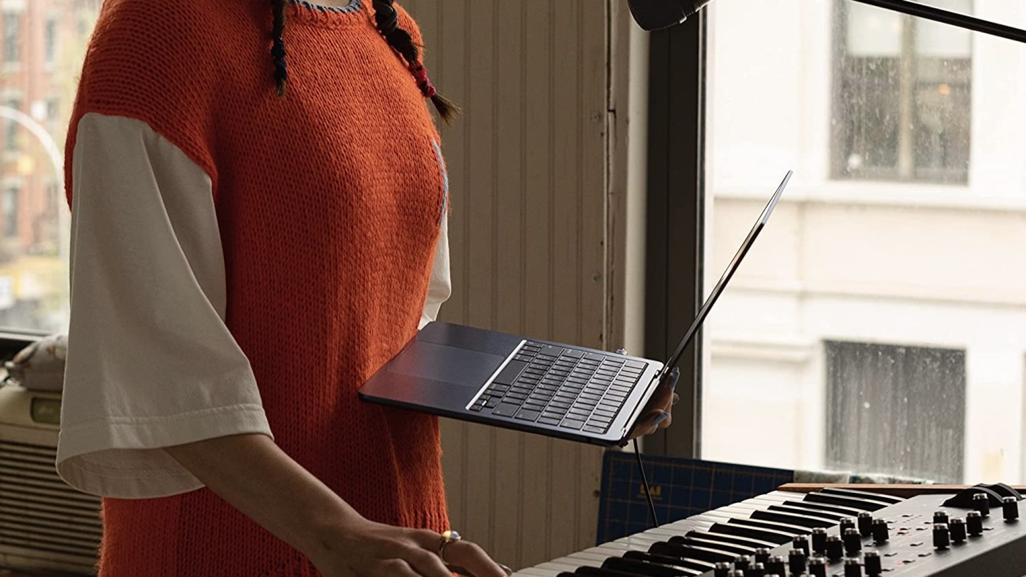 personne tenant un macbook air m2 devant un piano