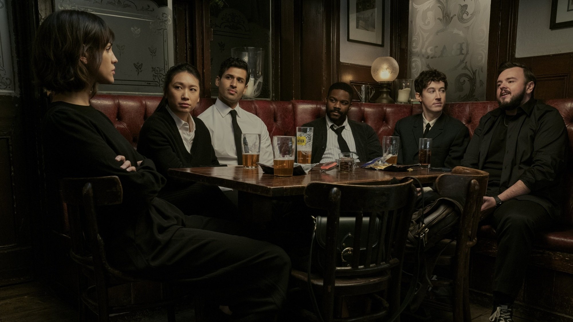 Un groupe d’amis vêtus de noir sont assis autour d’une table dans un pub.