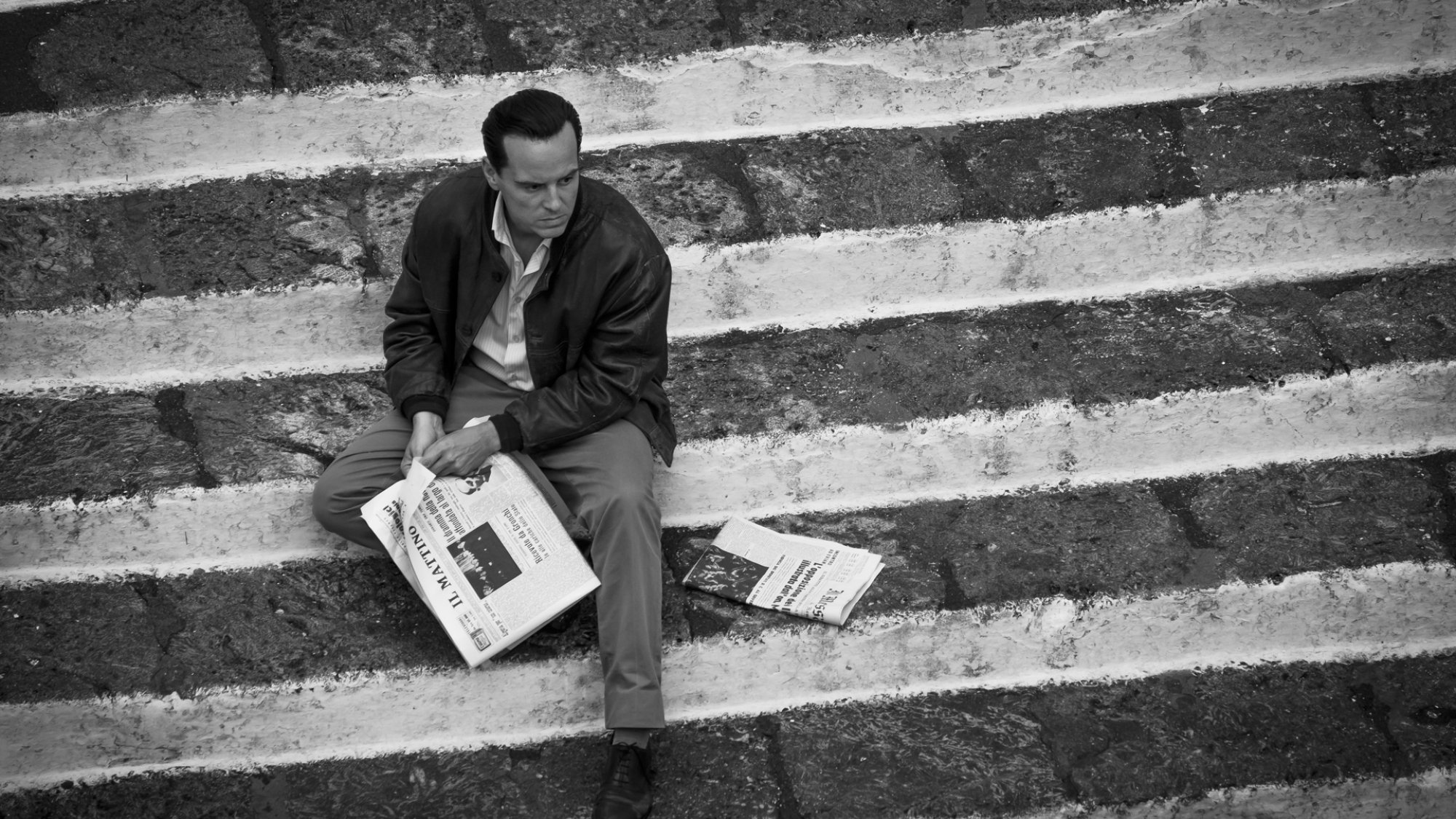 Un homme lit le journal dans un escalier.