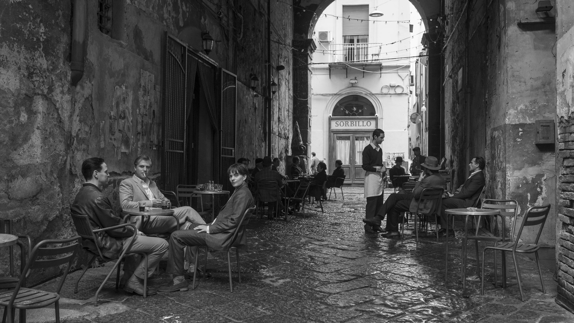 Trois personnes boivent du café dans une ruelle italienne.